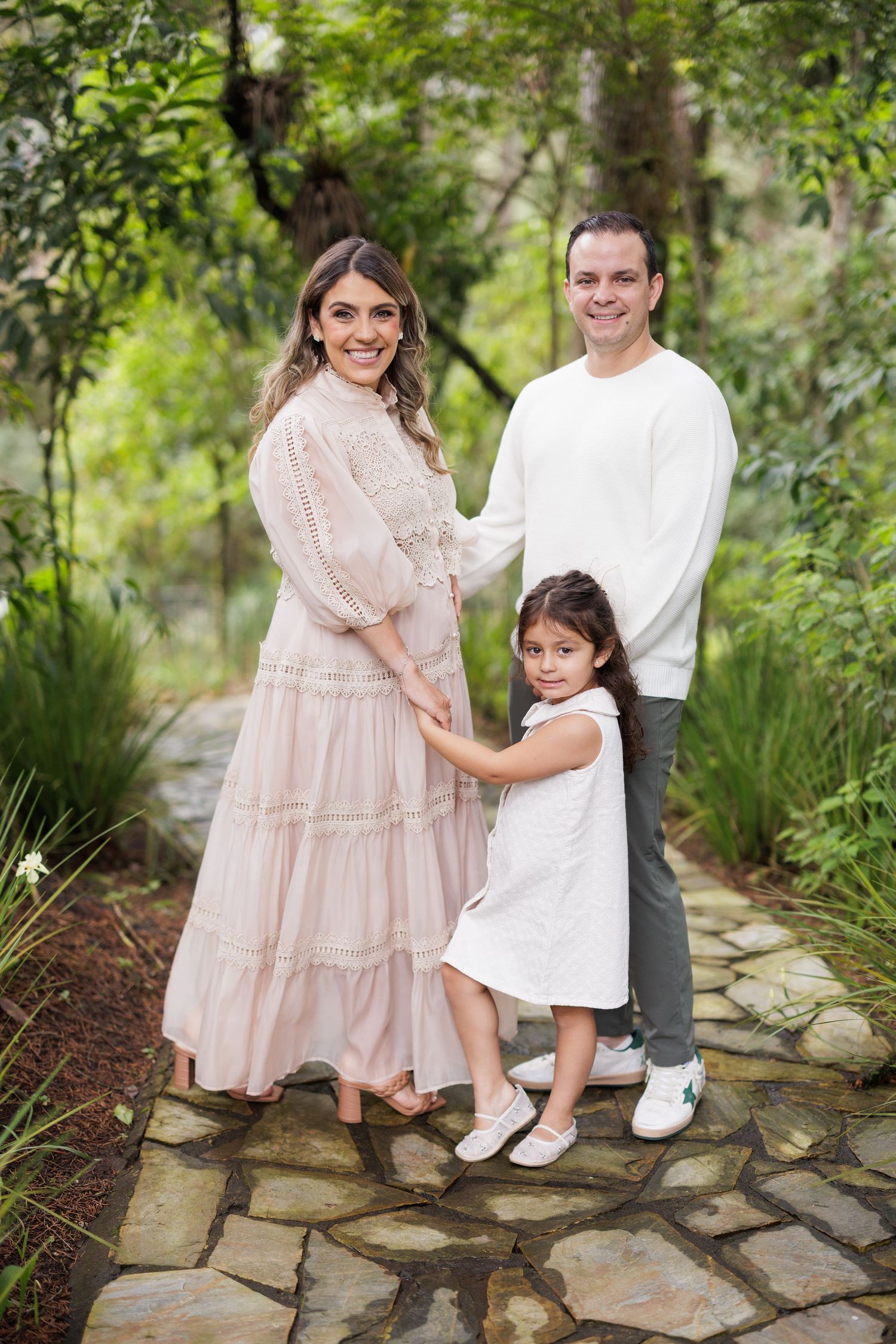 A family poses on stone pathways surrounded by lush garden greenery.