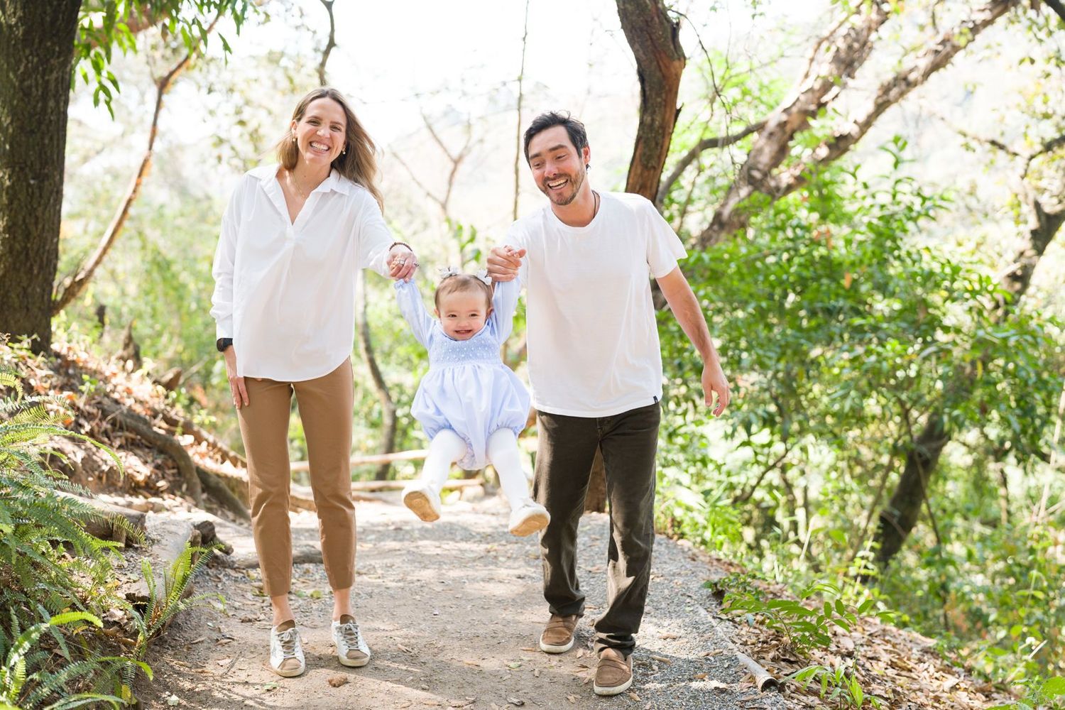 Family walks together on nature path under green tree canopy.