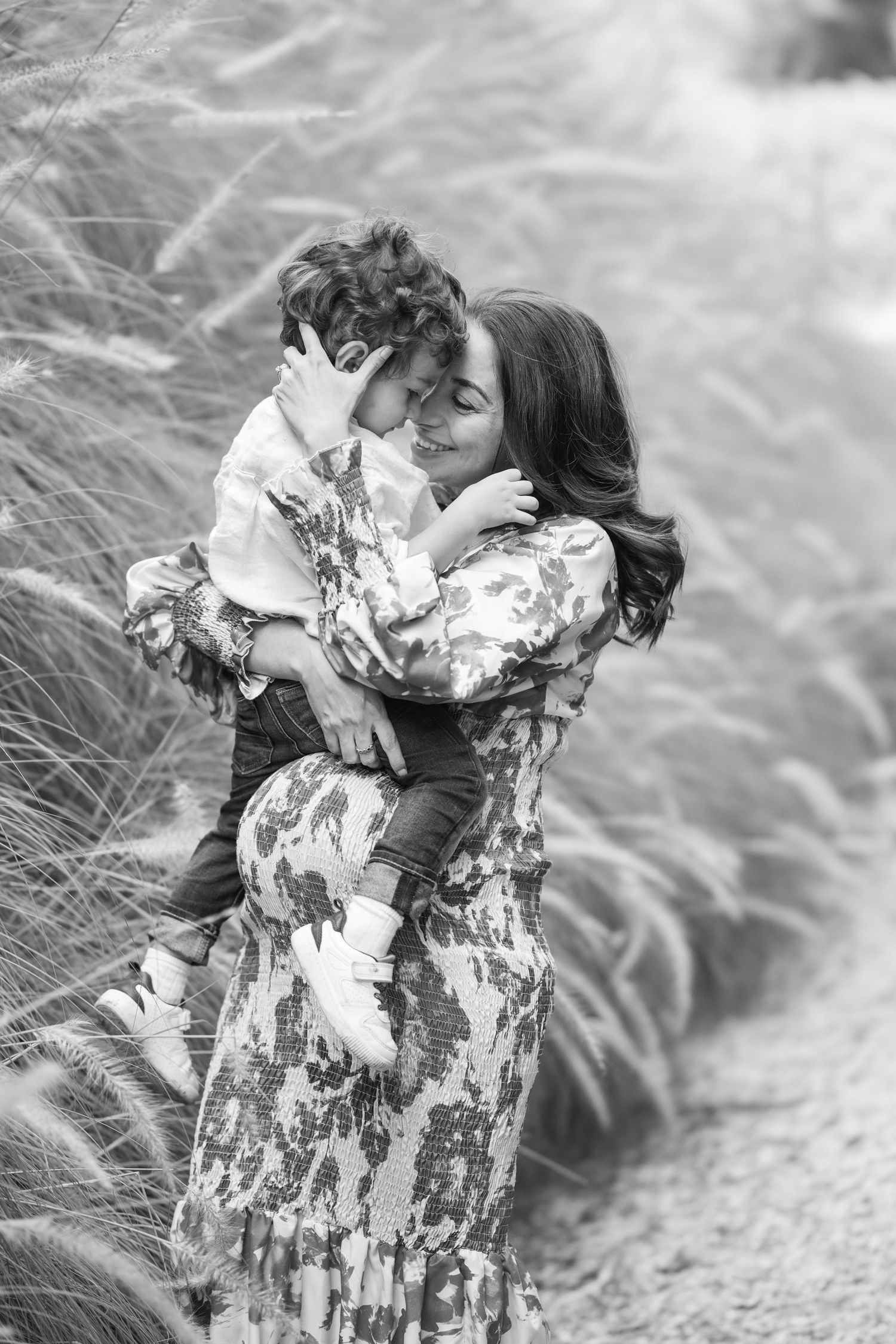 Black and white artistic photo of two people lying in tall grass.