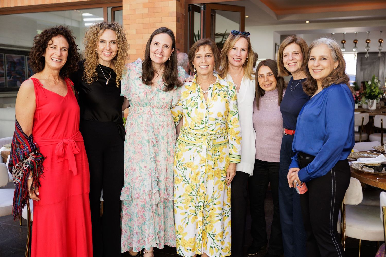 Group photo of people wearing colorful dresses at a social gathering.