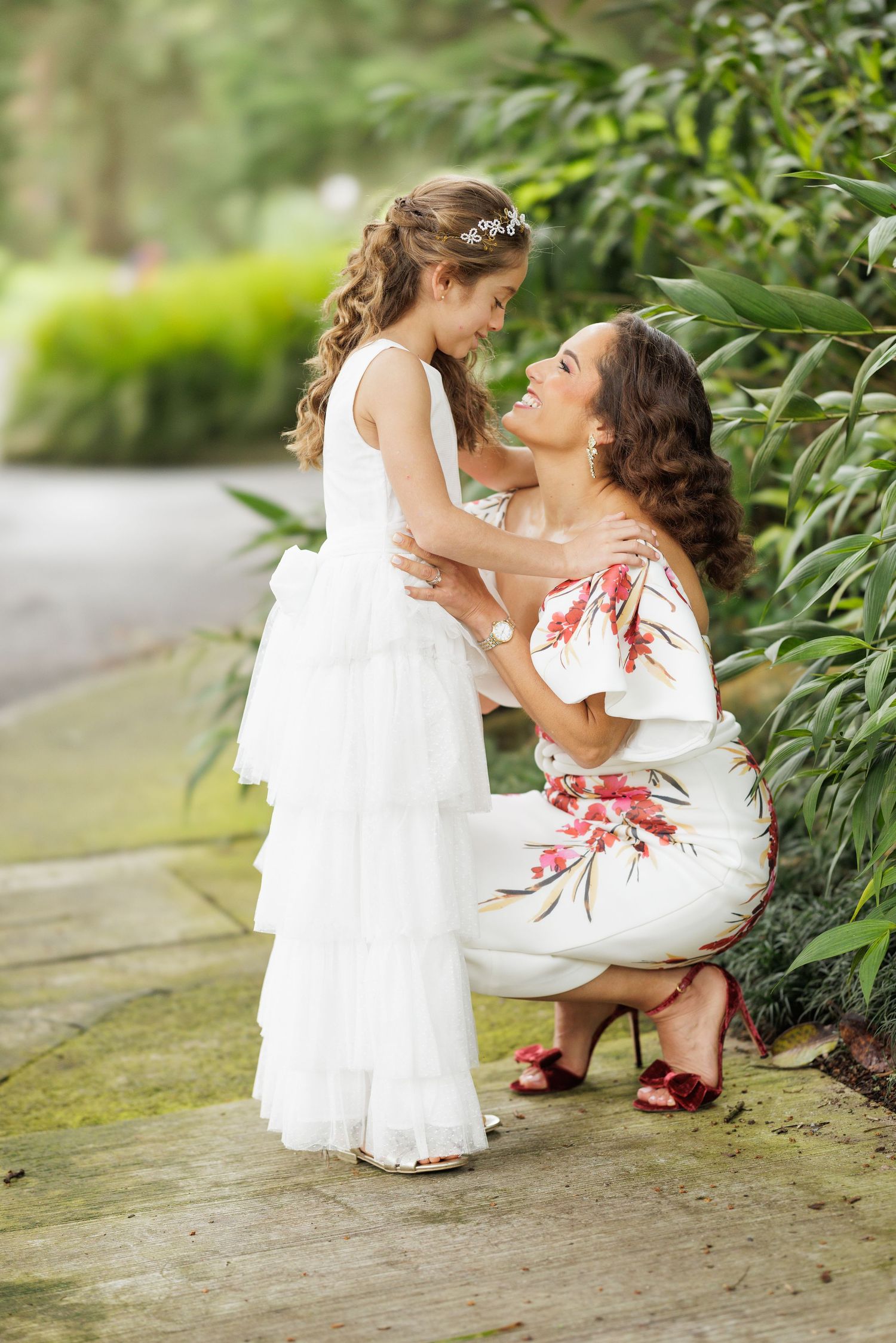 Sweet moment captured between two people in white dresses against a garden backdrop.