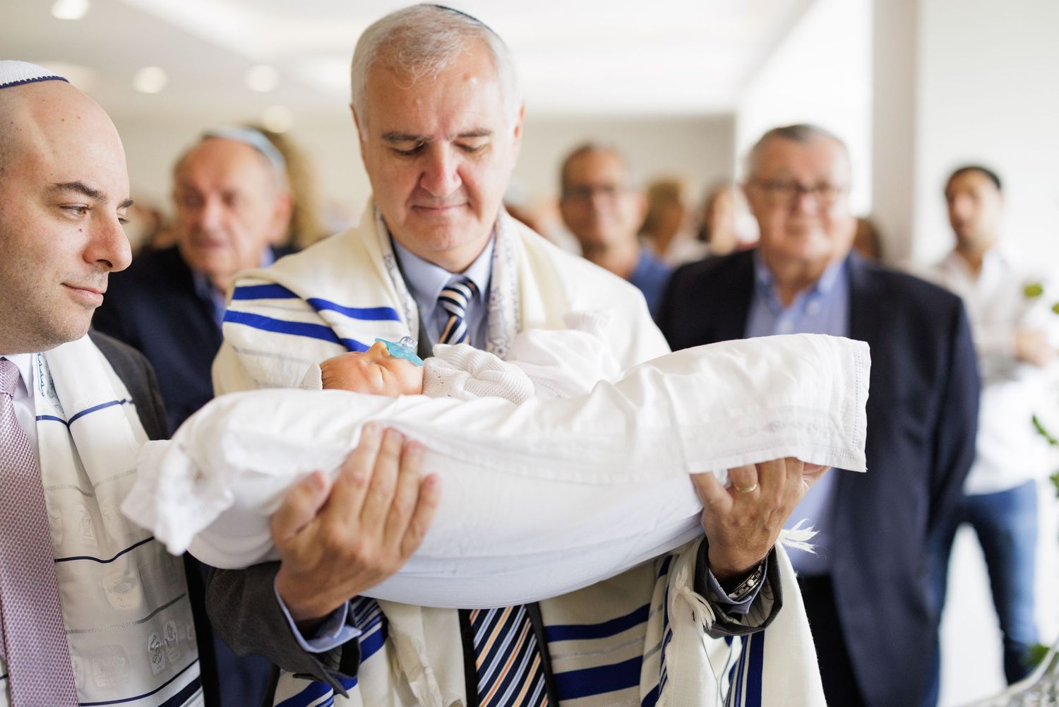 People gather around a ceremonial object wrapped in white fabric during a religious celebration.