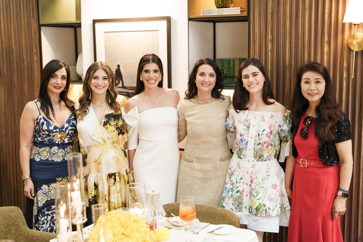 Group photo showing women in colorful dresses at a formal event with elegant decor.