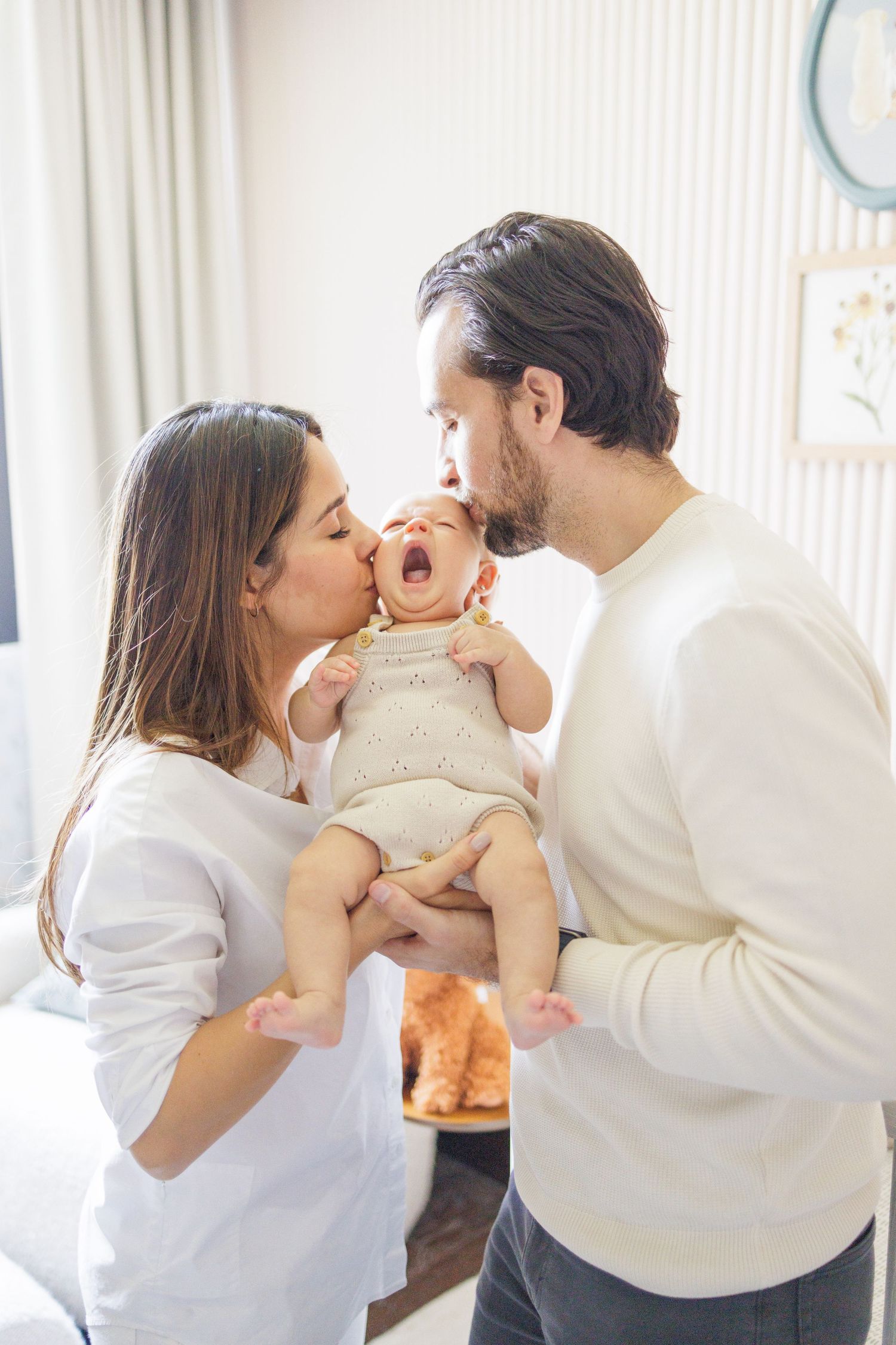 Family sharing loving moments with baby in bright indoor setting.