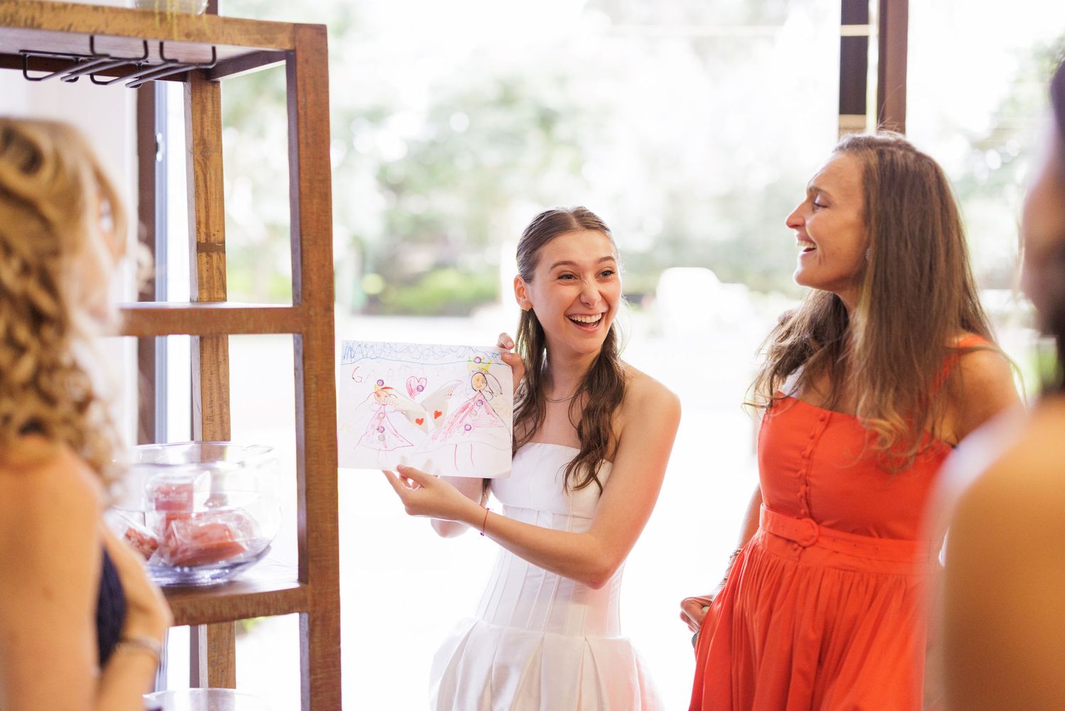 Bridal party wearing coral and white dresses share joyful moments together.