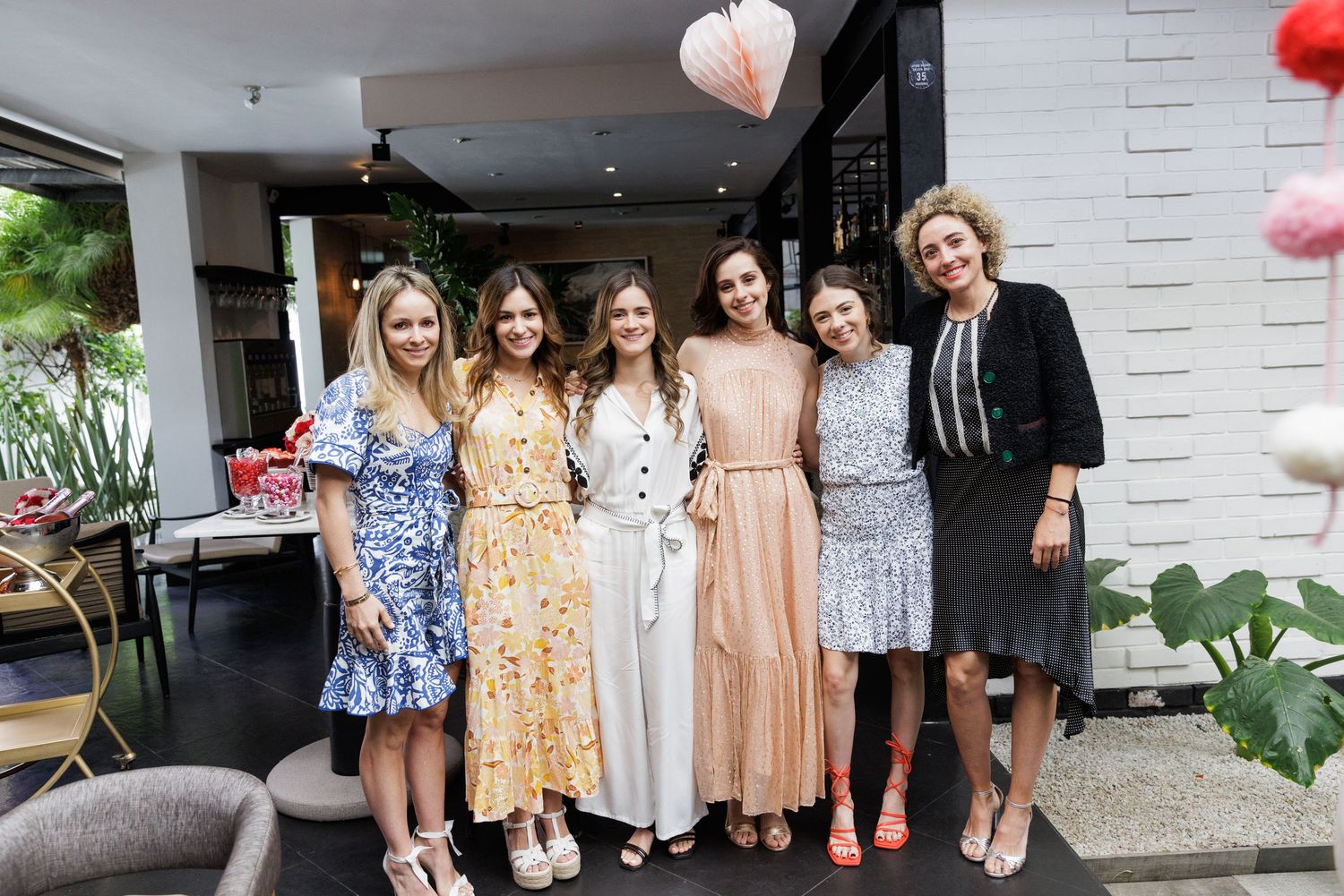 A group poses together in floral spring dresses at a social gathering.