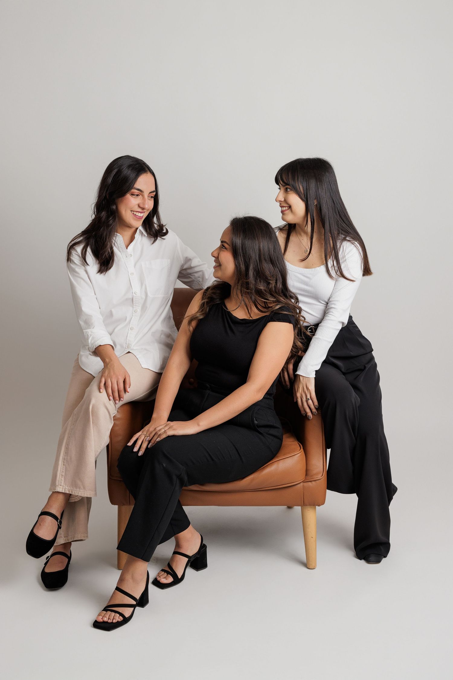 Casual group poses on brown leather chair wearing coordinated black and white outfits.