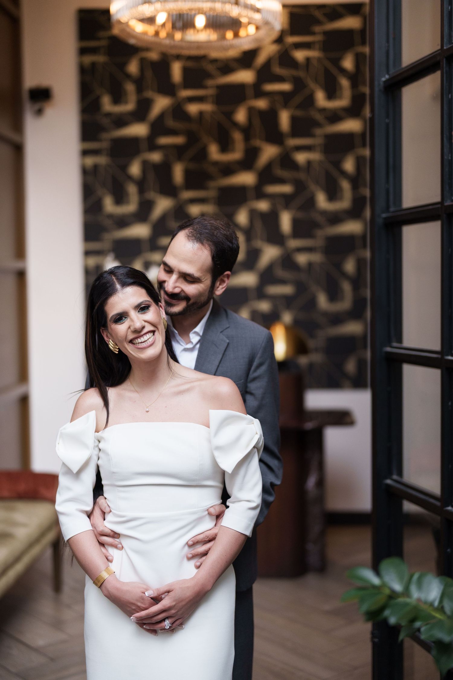 An elegant couple in formal wear sharing an intimate moment in a stylish interior setting.