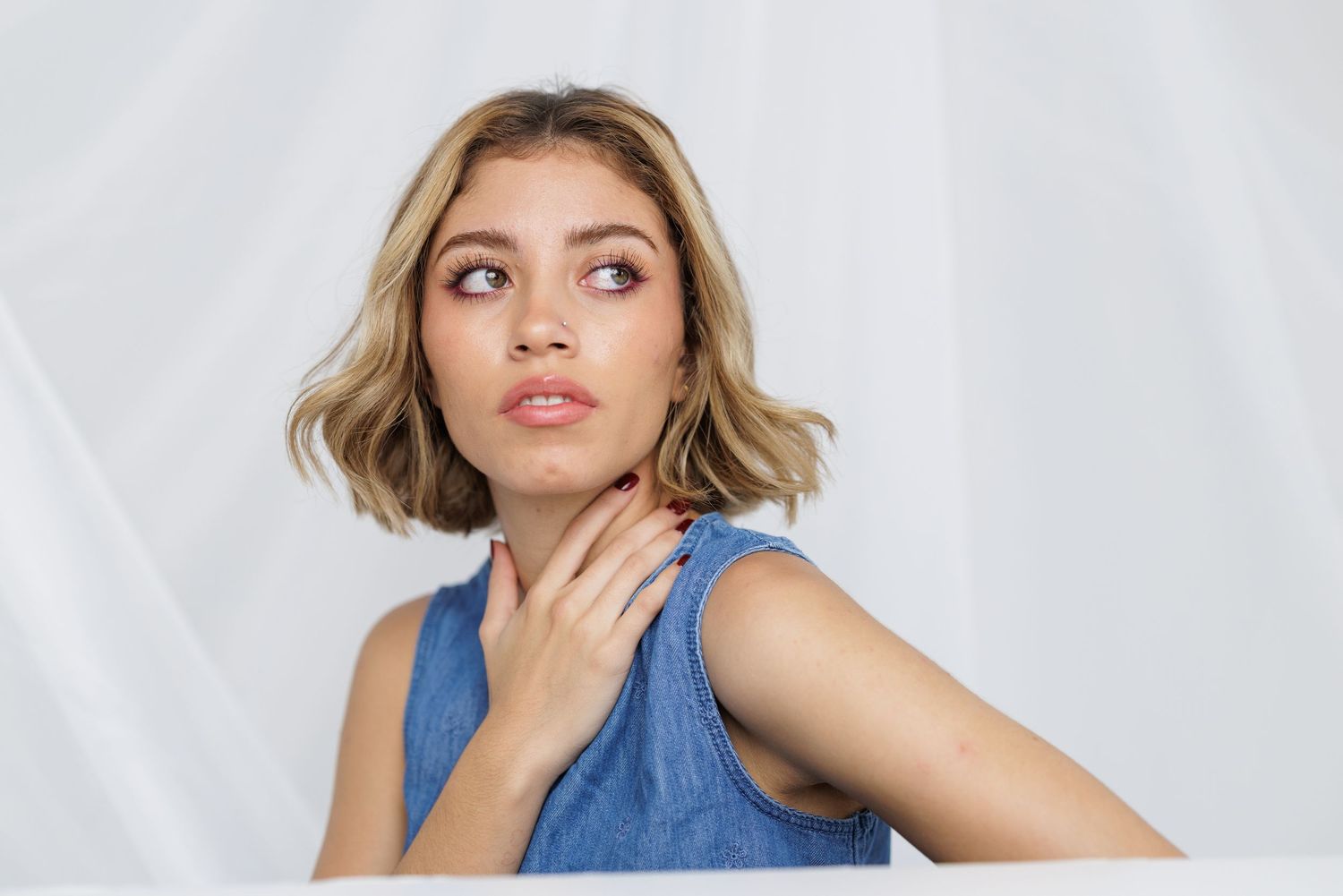 Fashion portrait in blue denim sleeveless top with dramatic lighting.