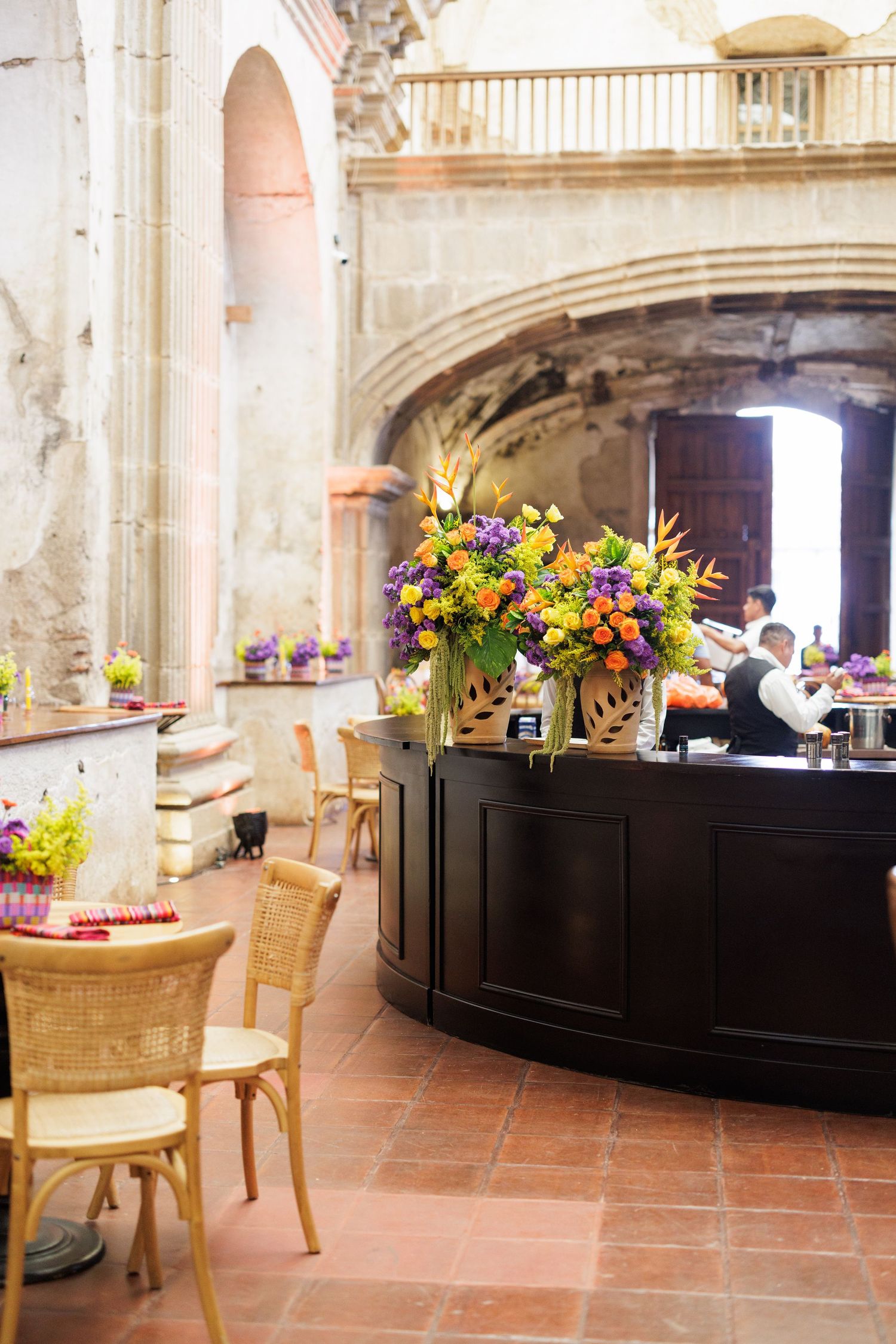 Interior view of historic venue with floral arrangements and bar setup for an event.