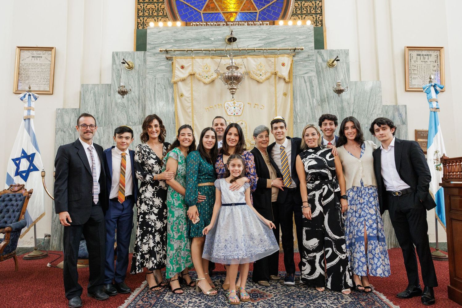 Large group gathered for a celebratory photo at a Jewish ceremony with traditional decorations.