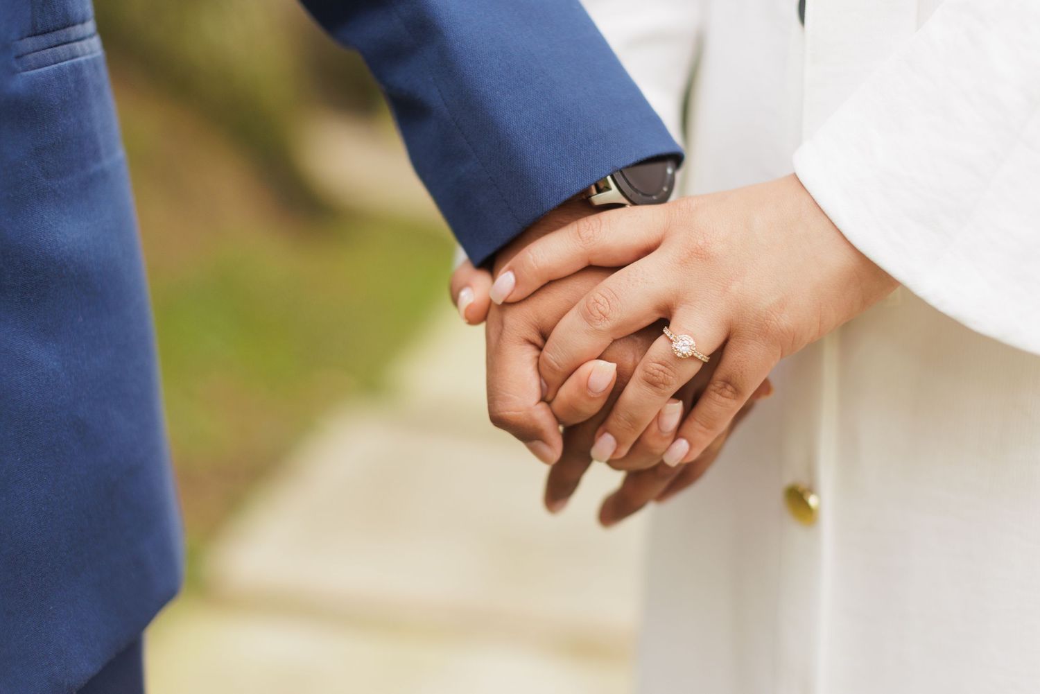 Close-up of hands with wedding rings intertwined against a white background.