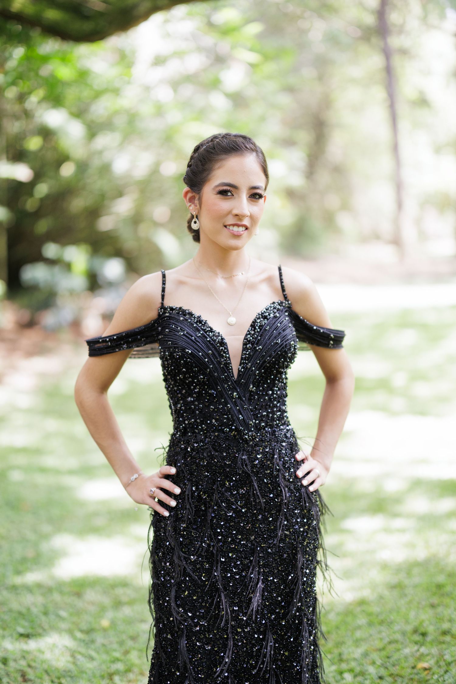 A person wearing a black sequined gown strikes various poses in a natural outdoor setting.