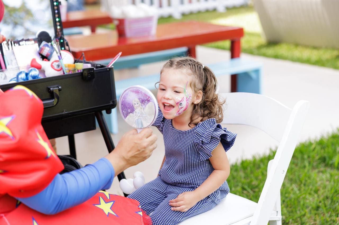 Young child in blue dress playing at outdoor activity station.