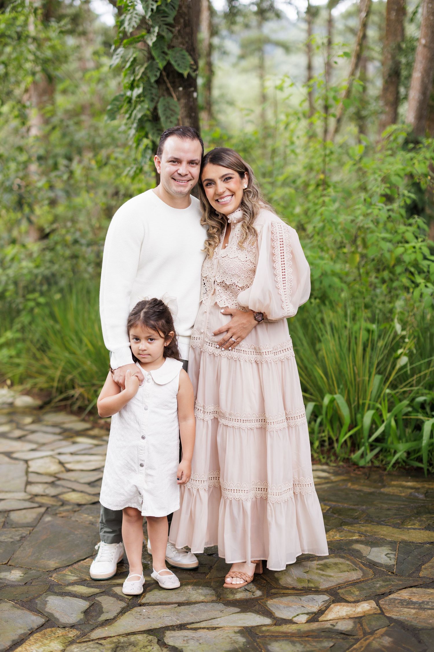 A family shares intimate moments on a stone path surrounded by tropical plants.