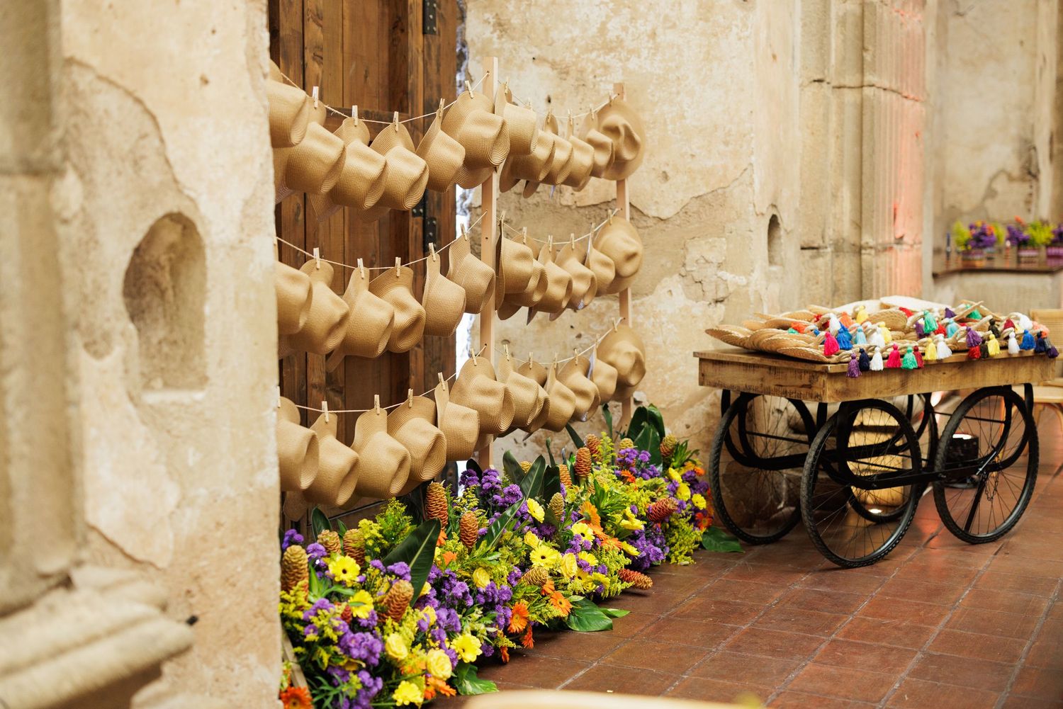 Wooden clogs and colorful flowers displayed along a rustic stone wall in an old European corridor.