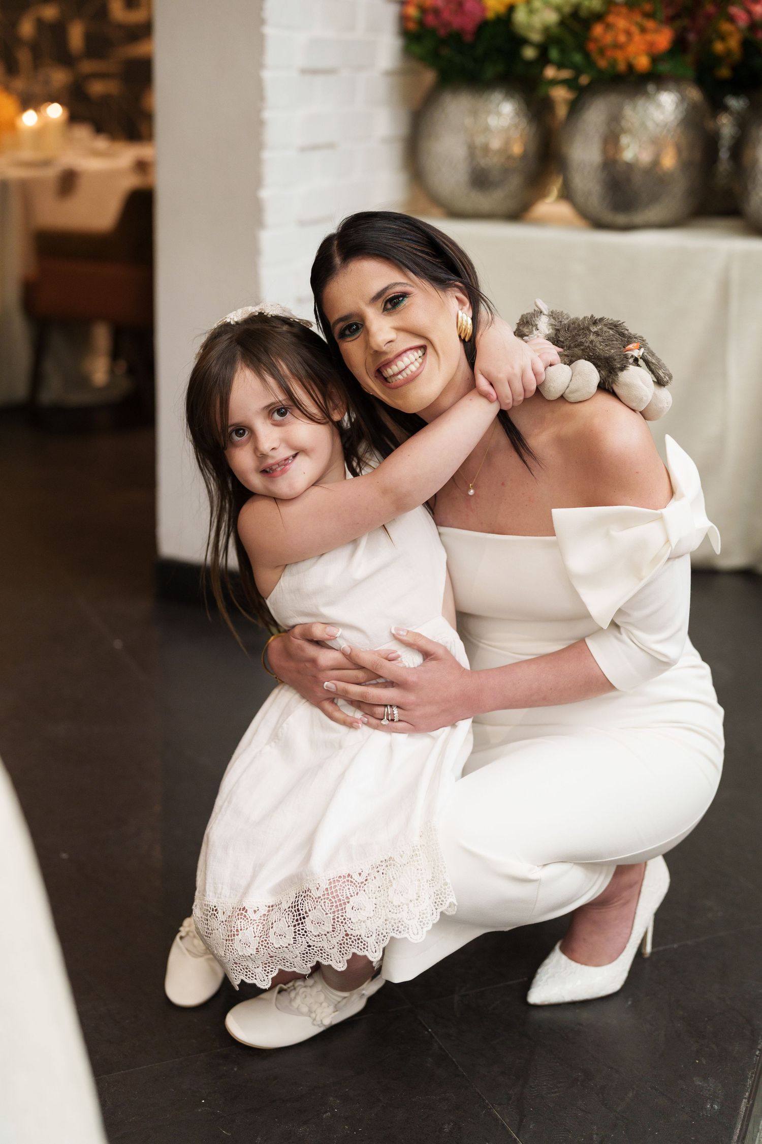 Two people in white dresses sharing a tender moment on a dark floor.
