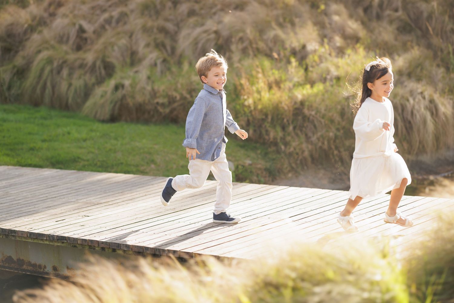 Children running and playing on a wooden boardwalk during golden hour.