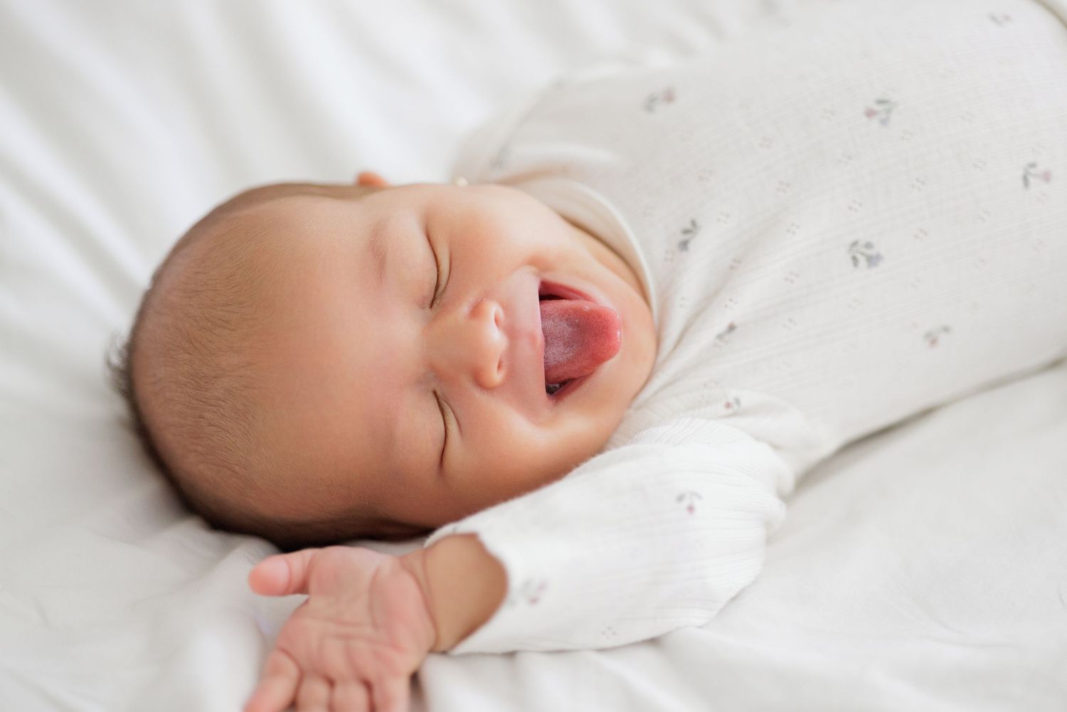 Closeup details of sleeping newborn baby on white bedding.