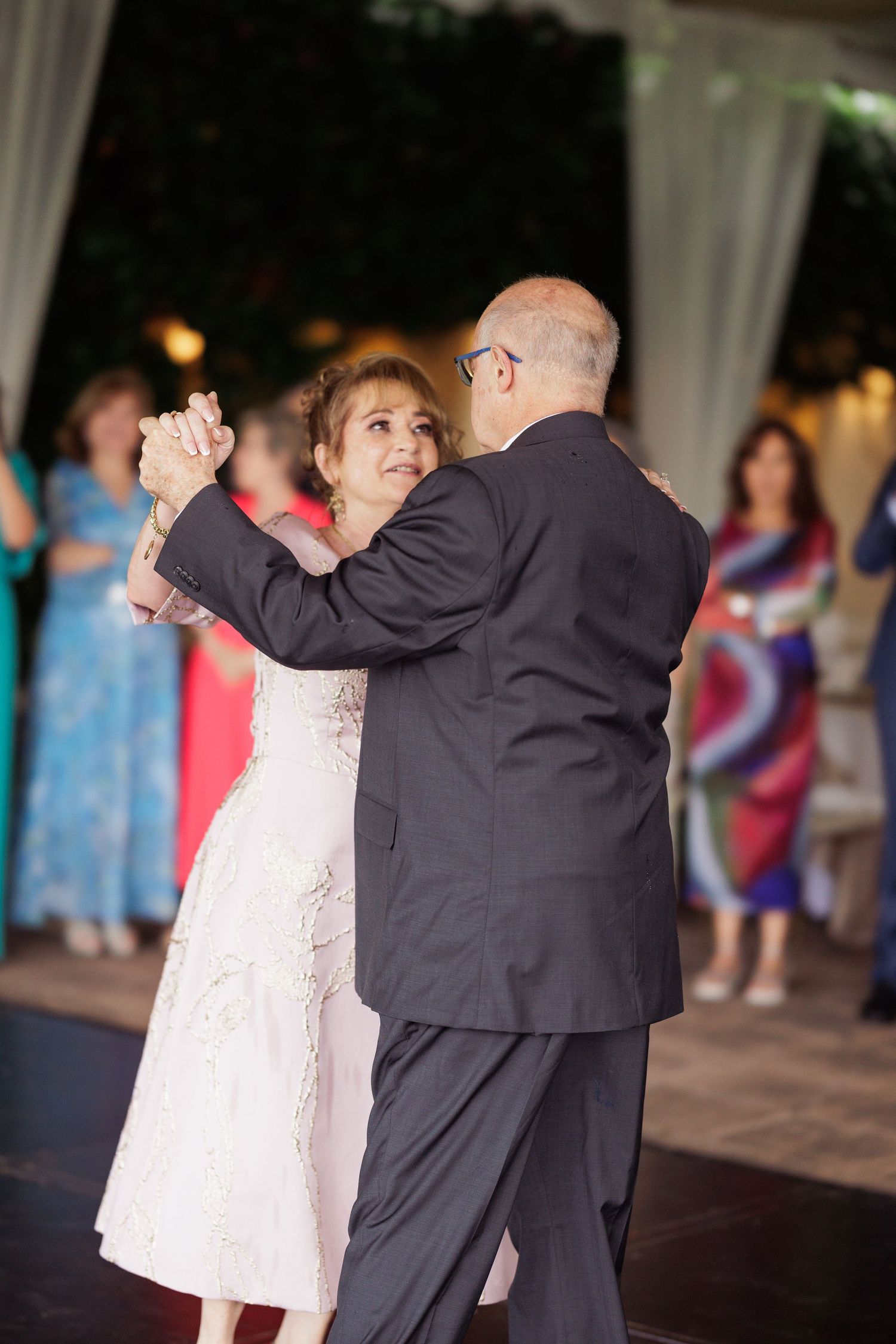 Couples dancing together at an evening reception under white drapes.