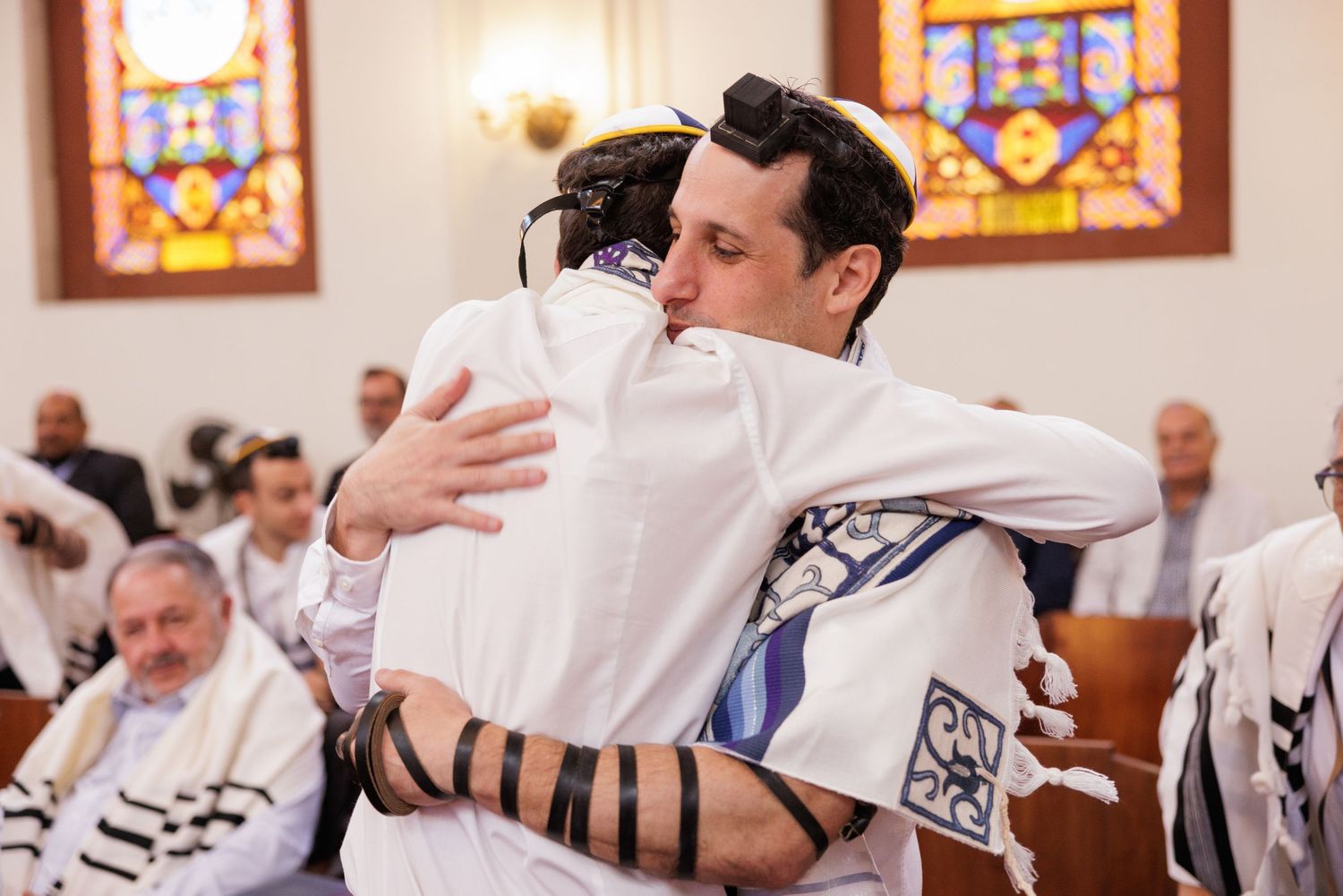People wearing traditional Jewish prayer garments during a synagogue service.