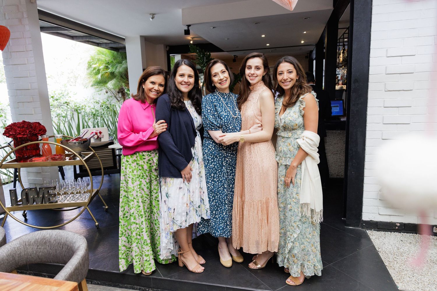 Group gathering in floral dresses at an indoor venue.