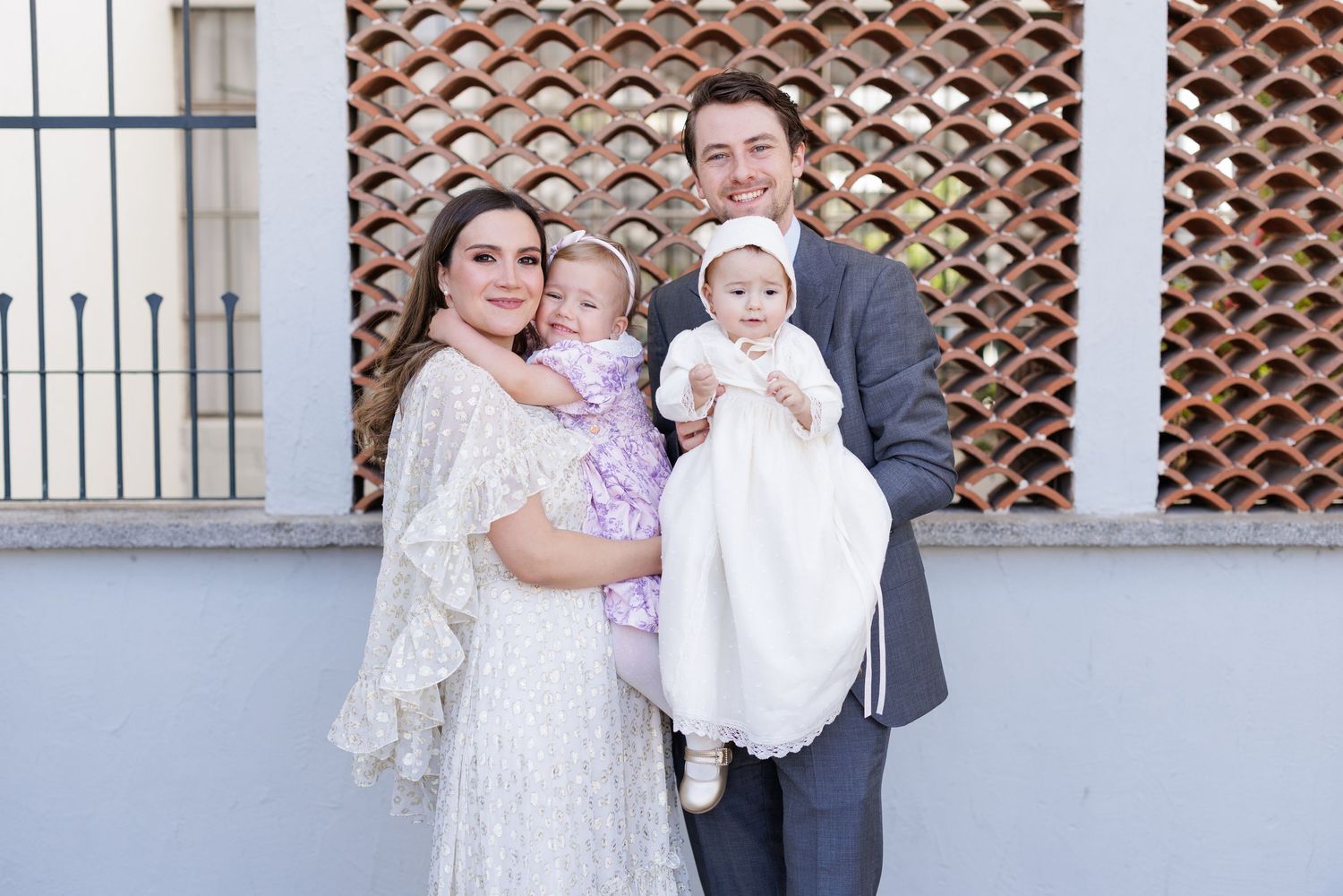 Family poses together in formal attire against textured wall background.