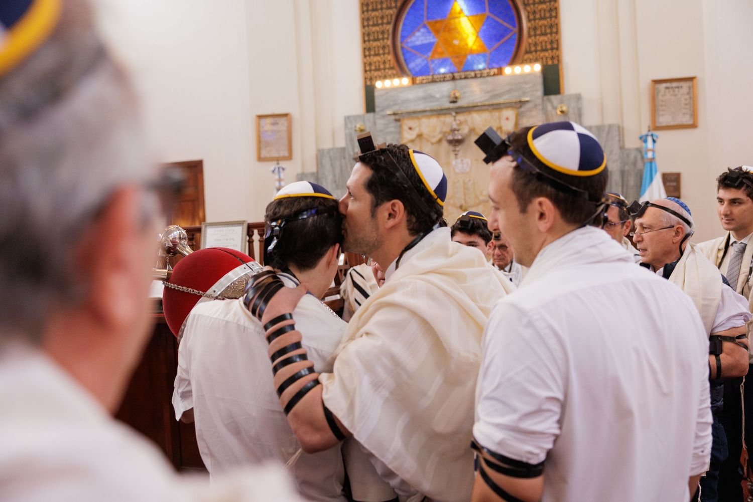 People in white prayer shawls standing together during a Jewish religious ceremony.