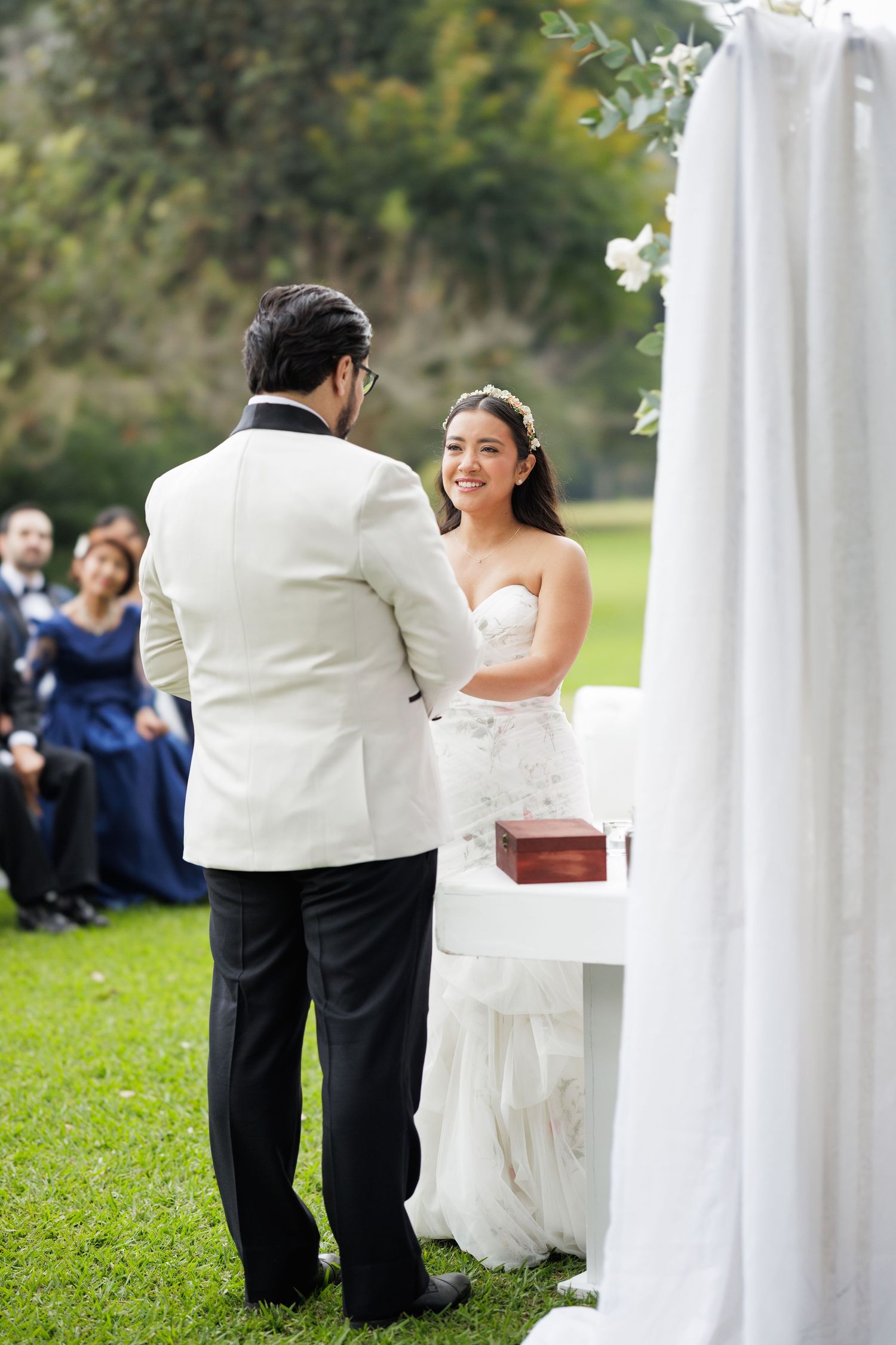 Wedding couple shares intimate moments behind white fabric draping in an outdoor garden setting.