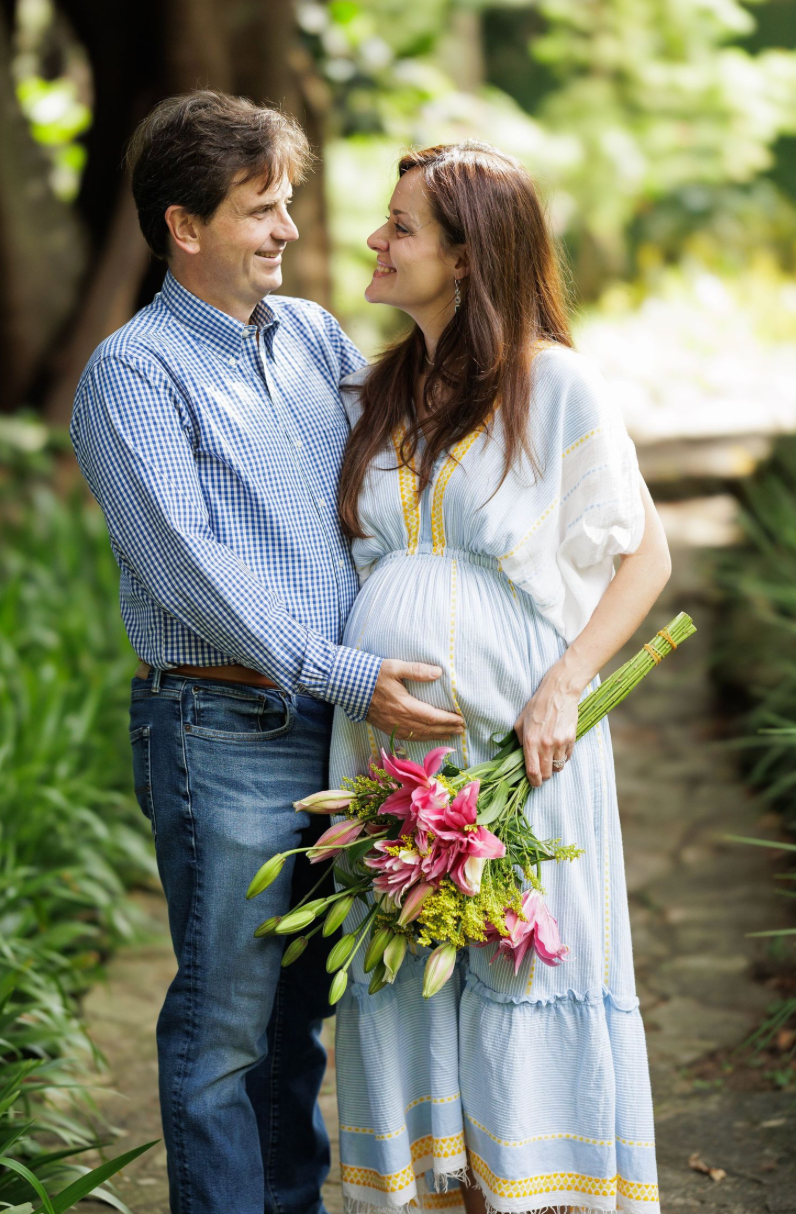 Romantic outdoor portrait with couple holding tropical flowers in a garden path setting.