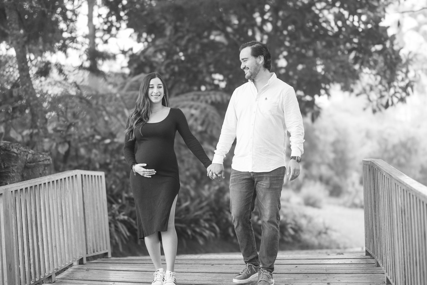 A couple walking together on a wooden bridge in a romantic outdoor setting.
