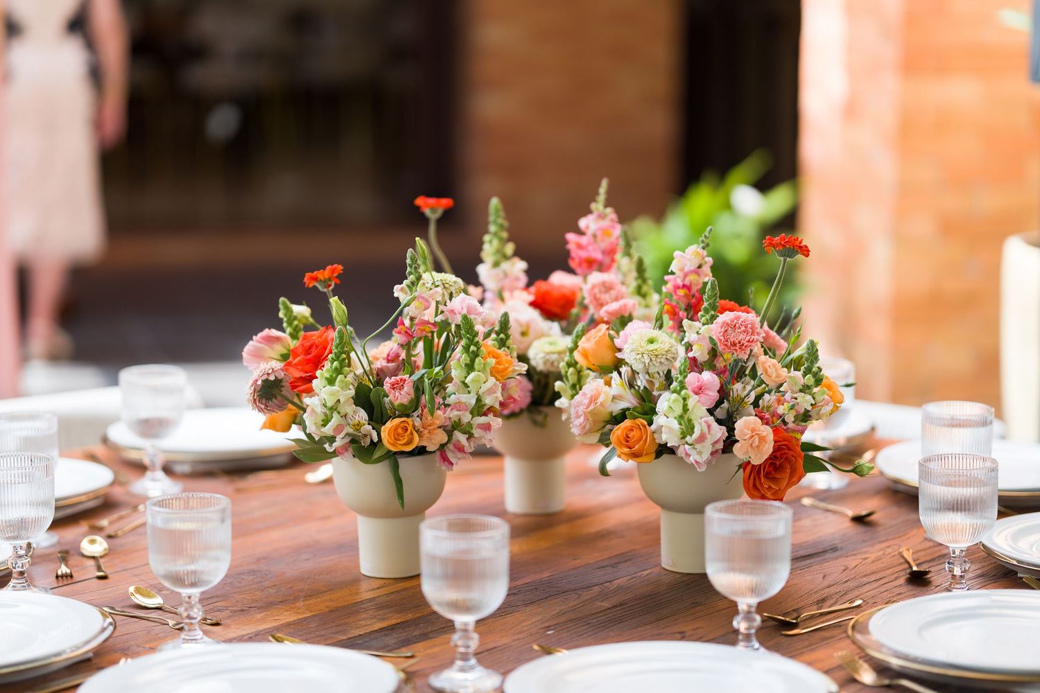 Elegant wooden table set for wedding reception with floral centerpieces and place settings.