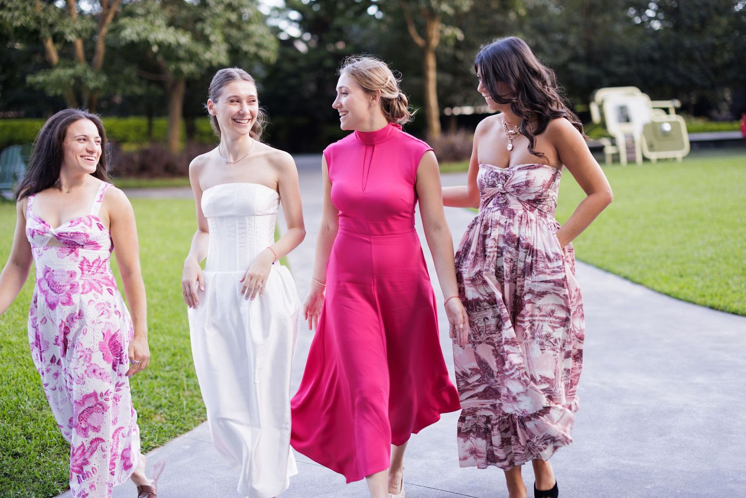 A group of friends in floral dresses walking together on an outdoor path.