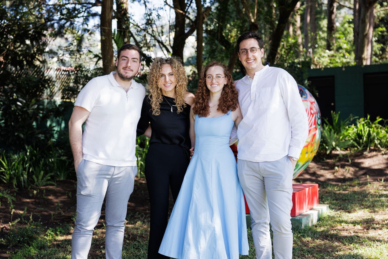 Group of people in casual attire gathered outdoors on a sunny day.