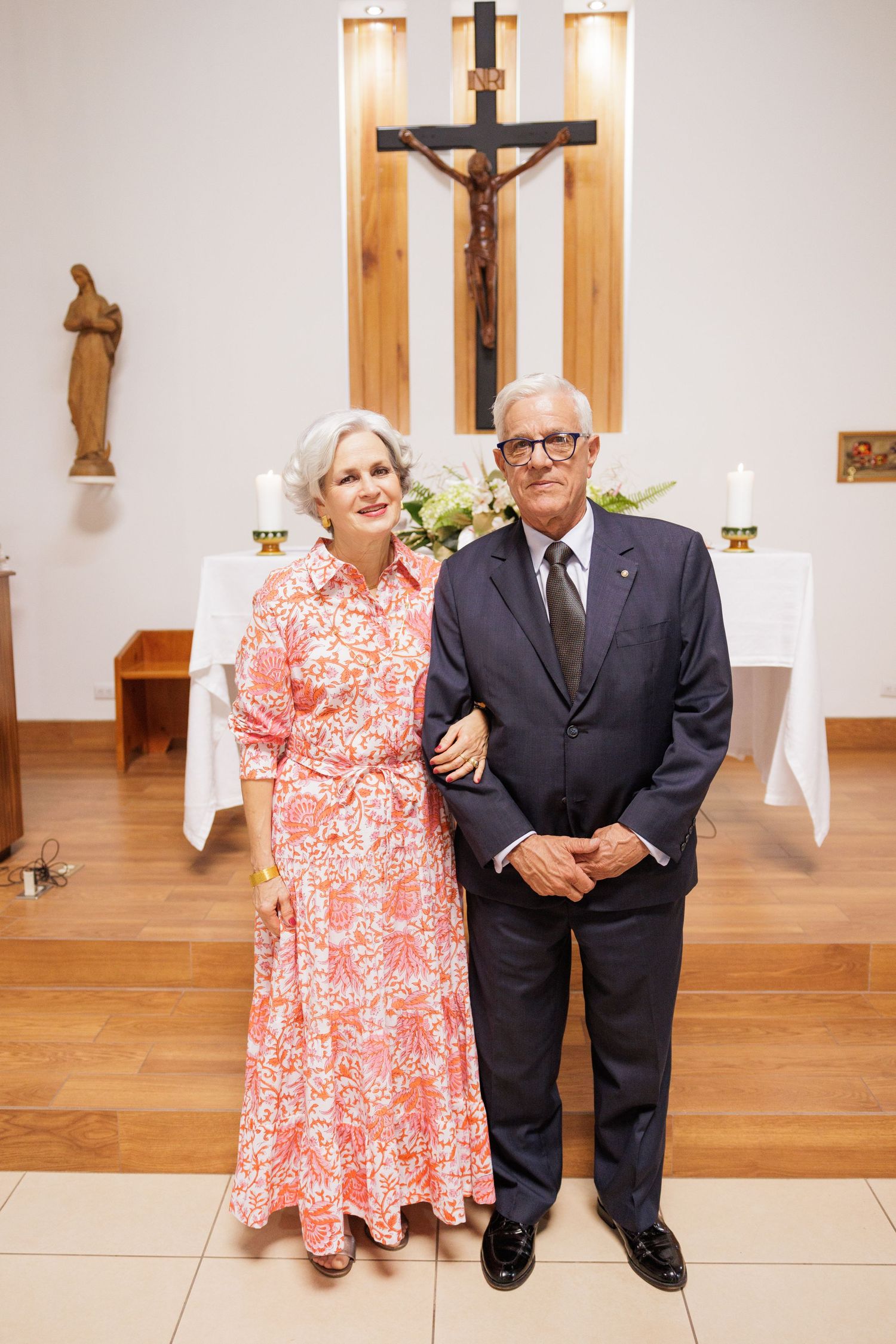 Couple in formal attire standing together in a church with wooden decor.