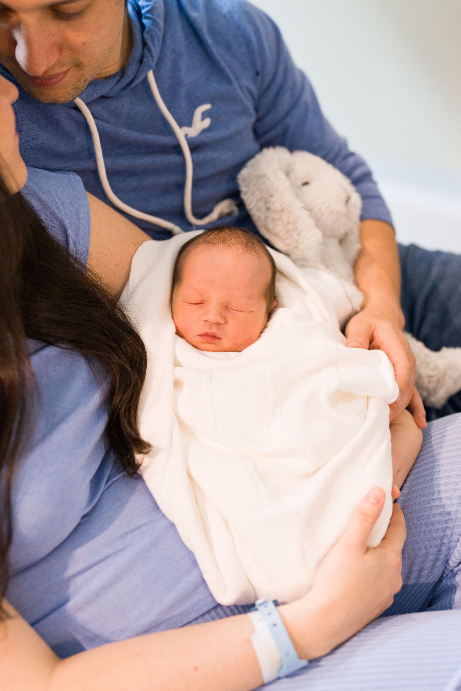 Close-up shots of parents holding their newborn baby wrapped in light pink blanket.