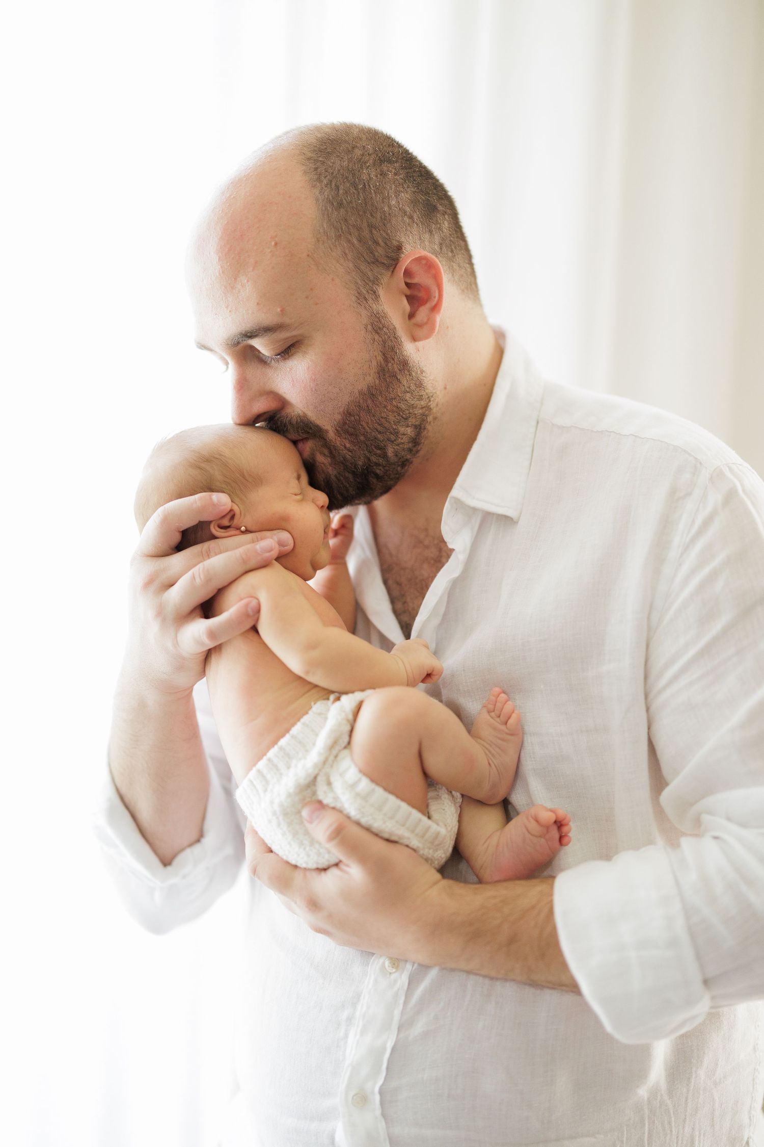 A tender moment captured in a series of black and white photos showing gentle kisses with a baby.