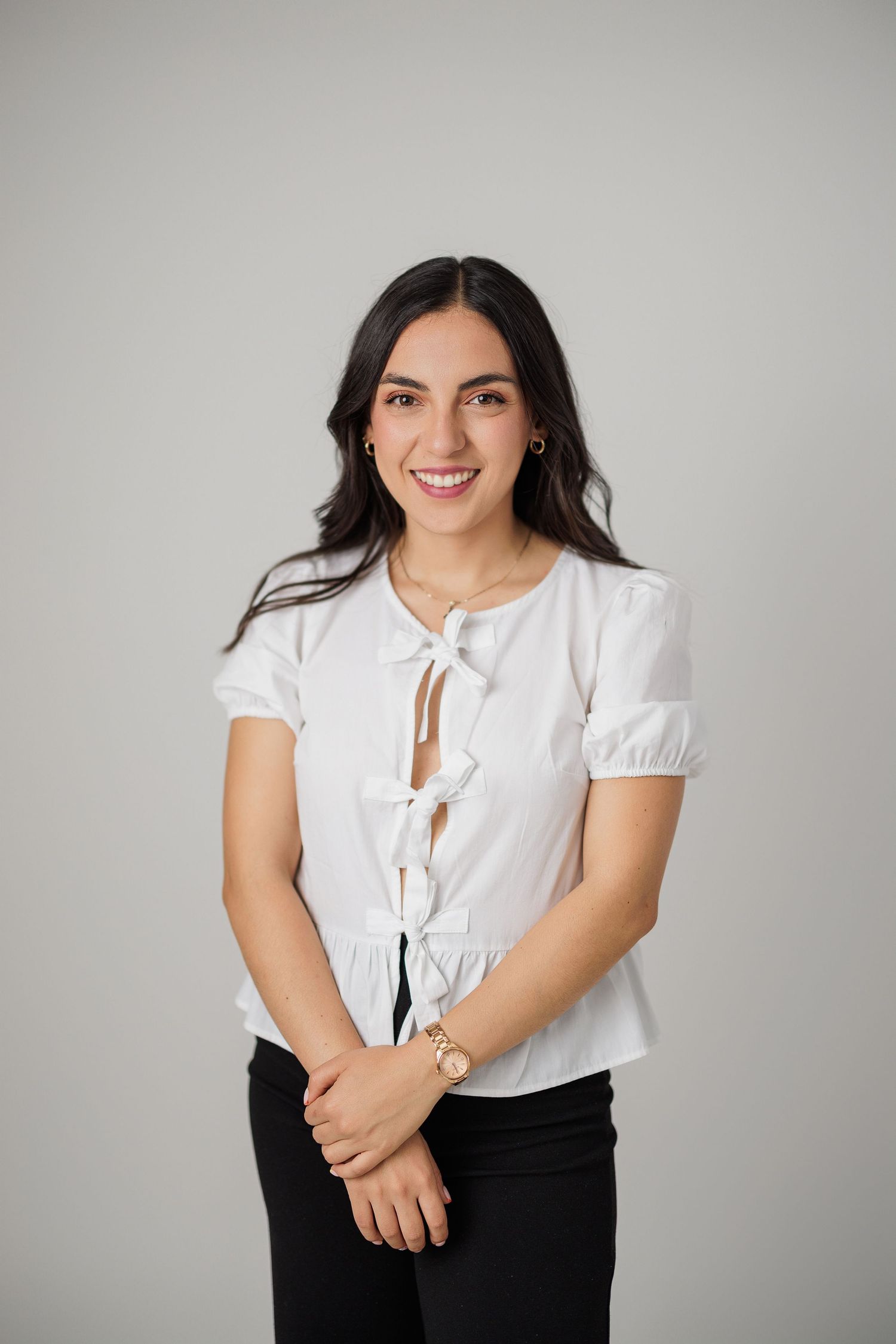 Studio portrait of someone in white blouse and black pants with playful expressions.