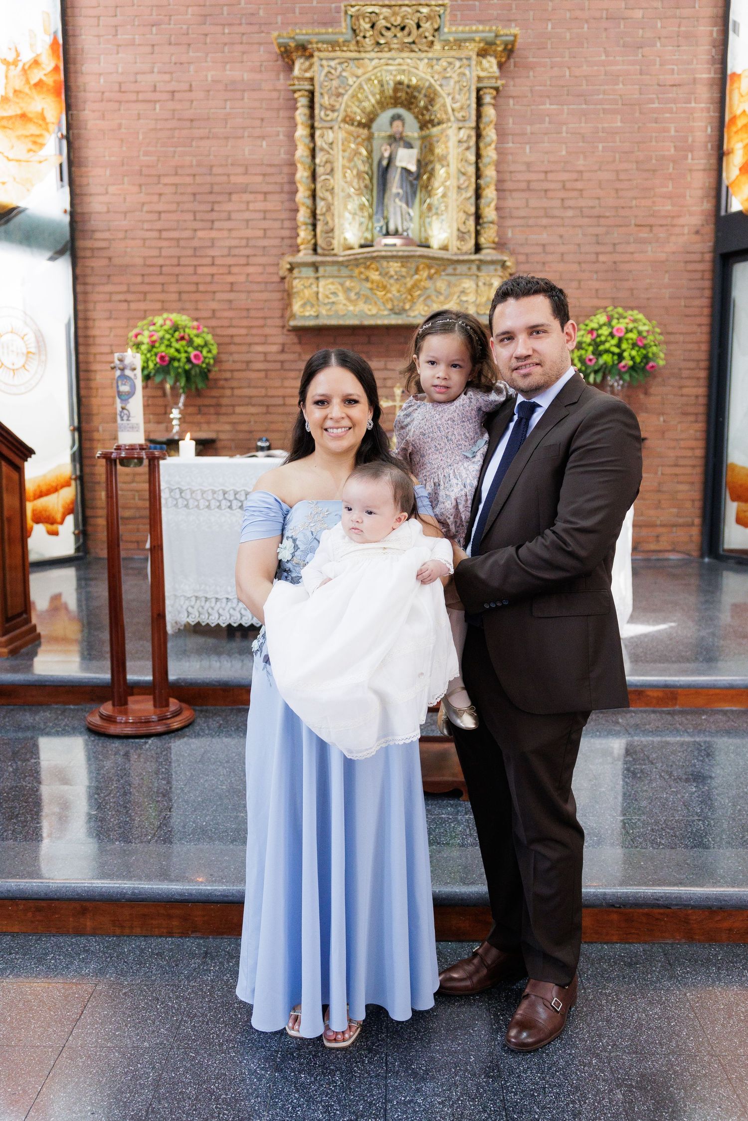 A family gathering at a church with ornate gold fixtures and brick walls.