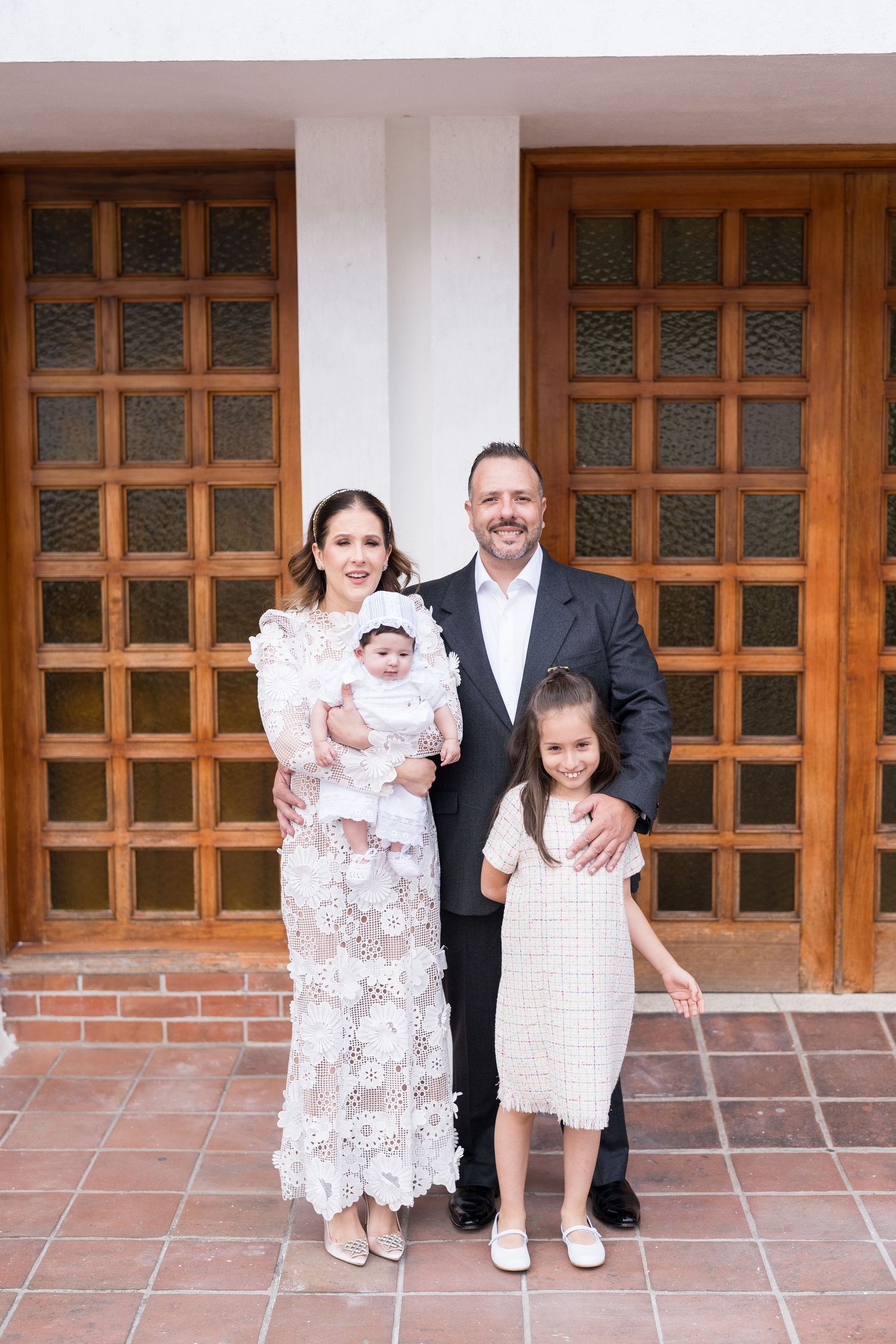 Family portrait in front of wooden doors and brick wall during special occasion.