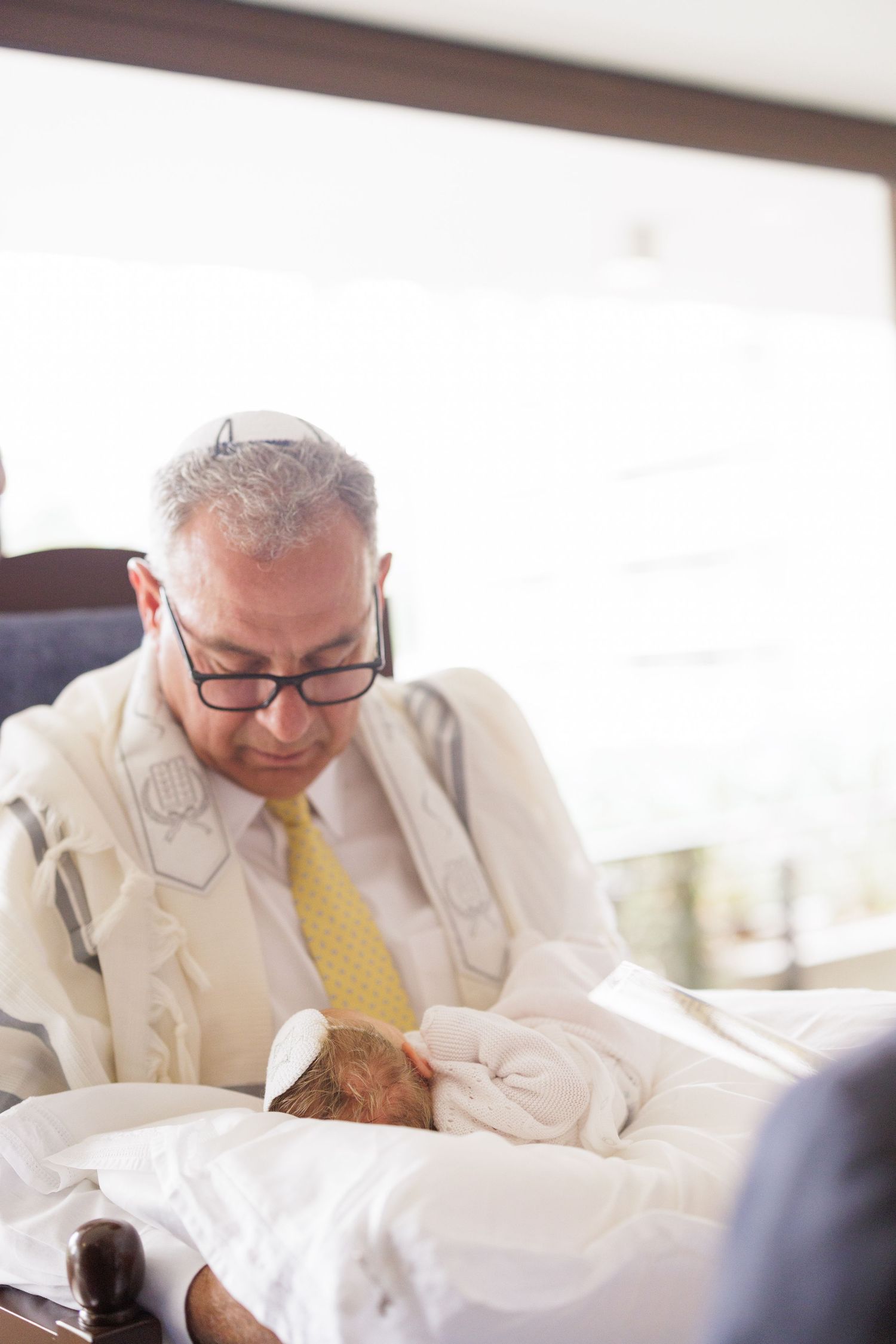 Person in light colored suit and yellow tie signing documents at a table.