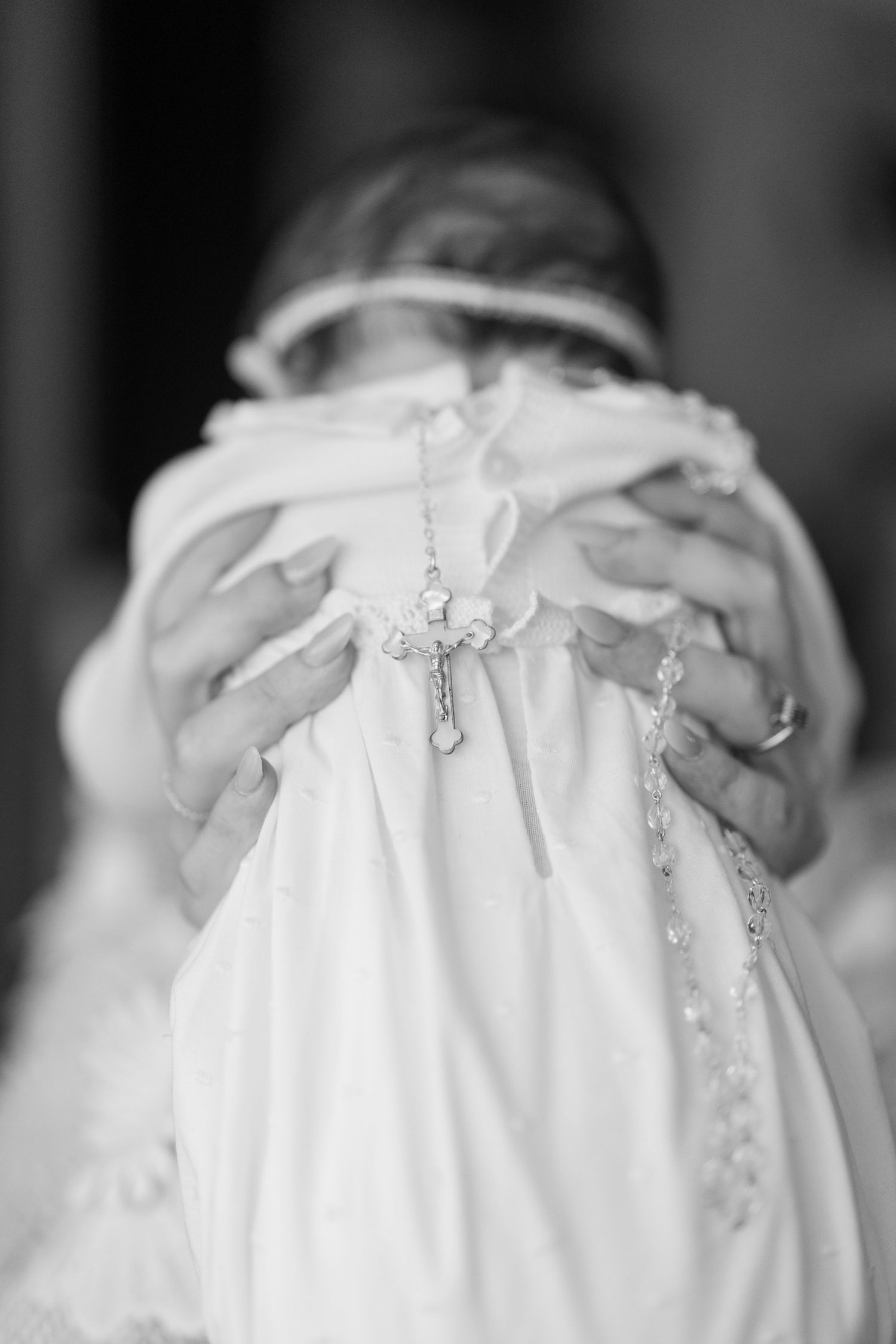 Close-up details of a white christening gown with delicate embroidery and lace.