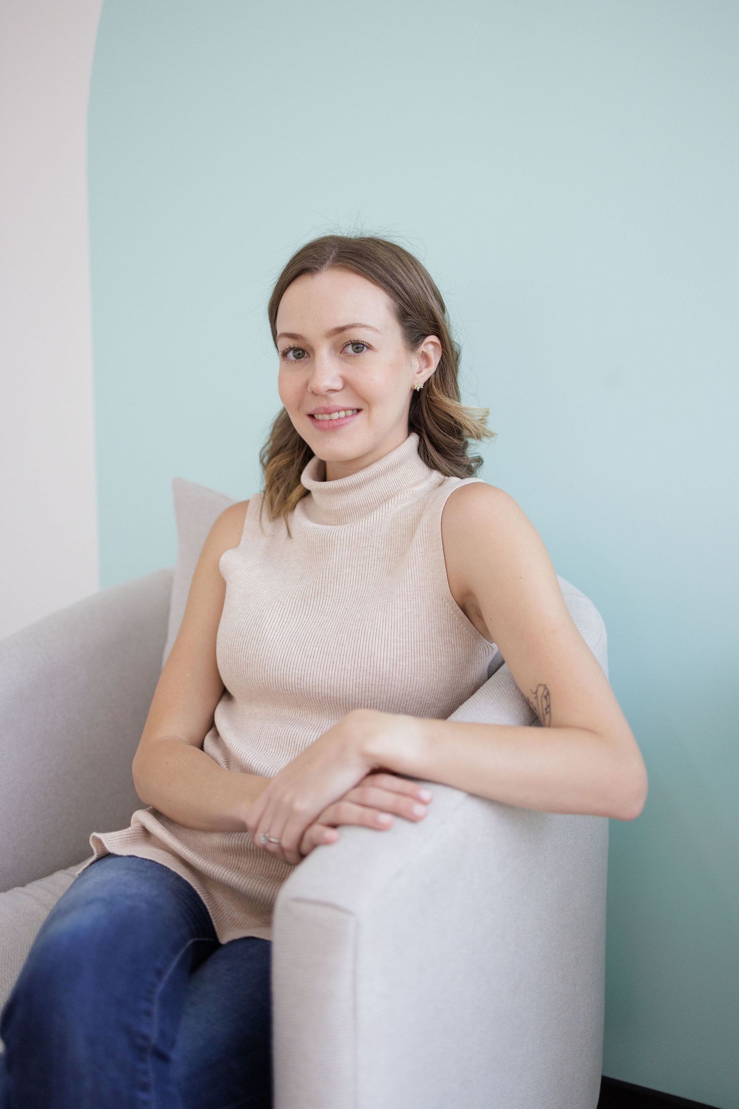 Person sitting comfortably in white chair against light blue wall.