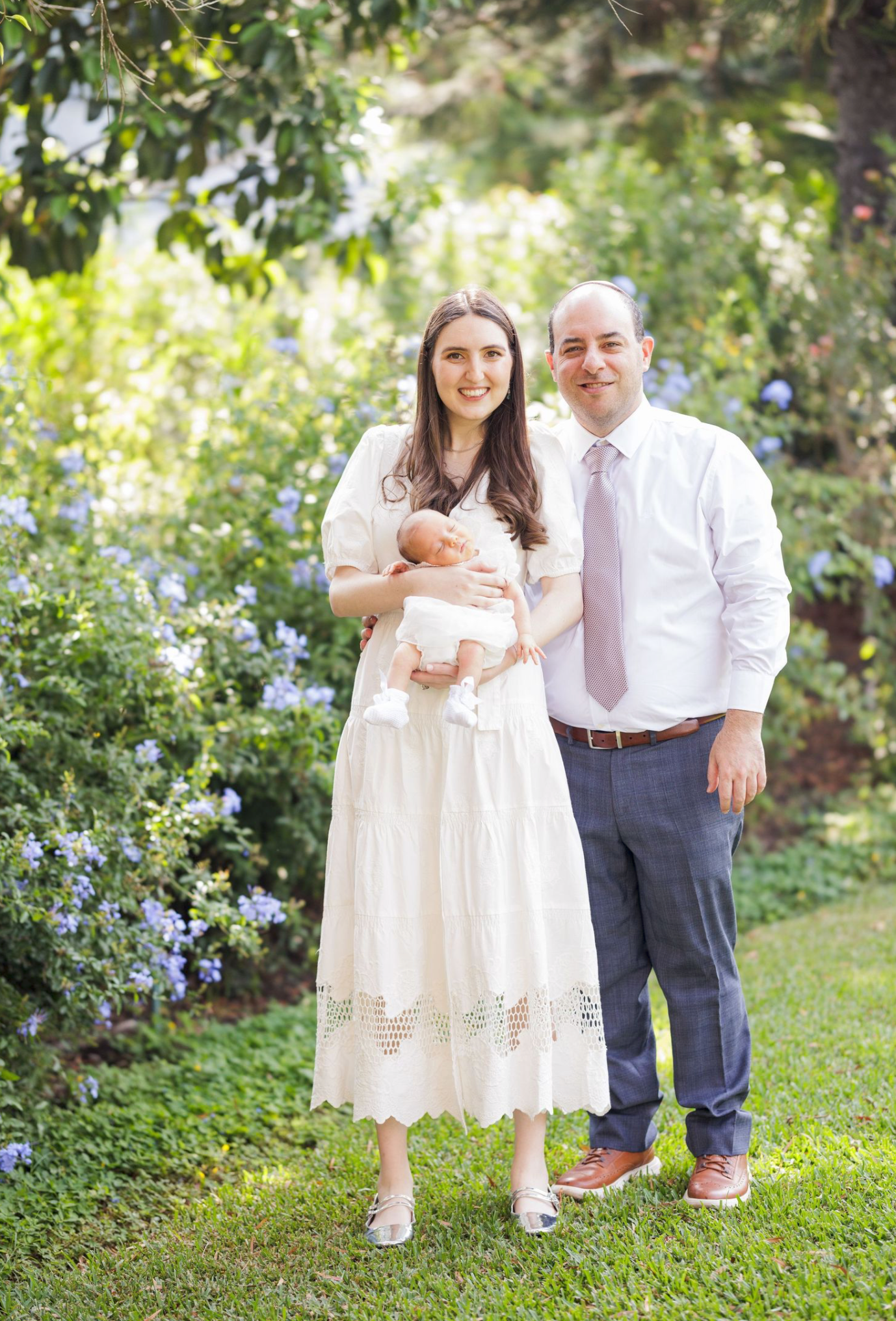 Family portrait in a garden with children wearing white dresses and formal attire.