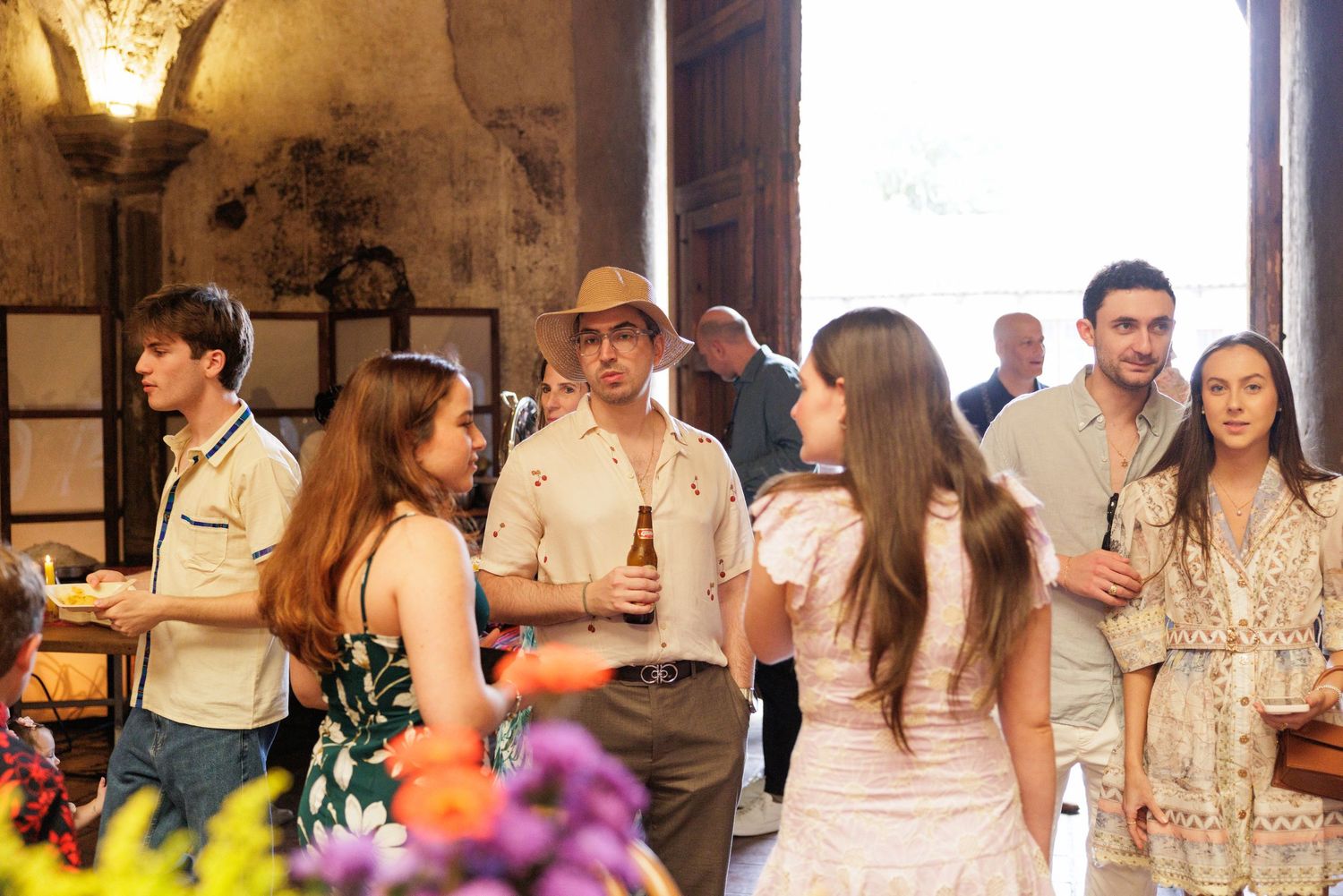 Event guests mingling in rustic stone venue with natural lighting from windows.