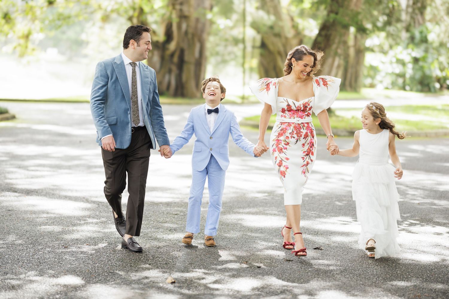A group walks together on a sunlit path during a formal celebration.