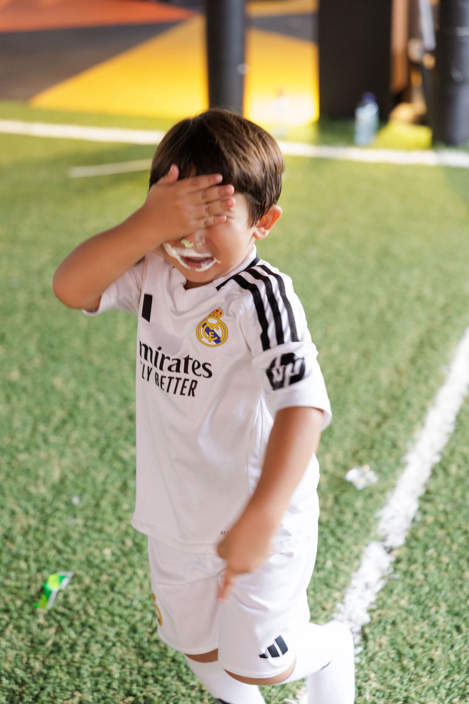 Young soccer player in Real Madrid uniform practicing on a turf field.