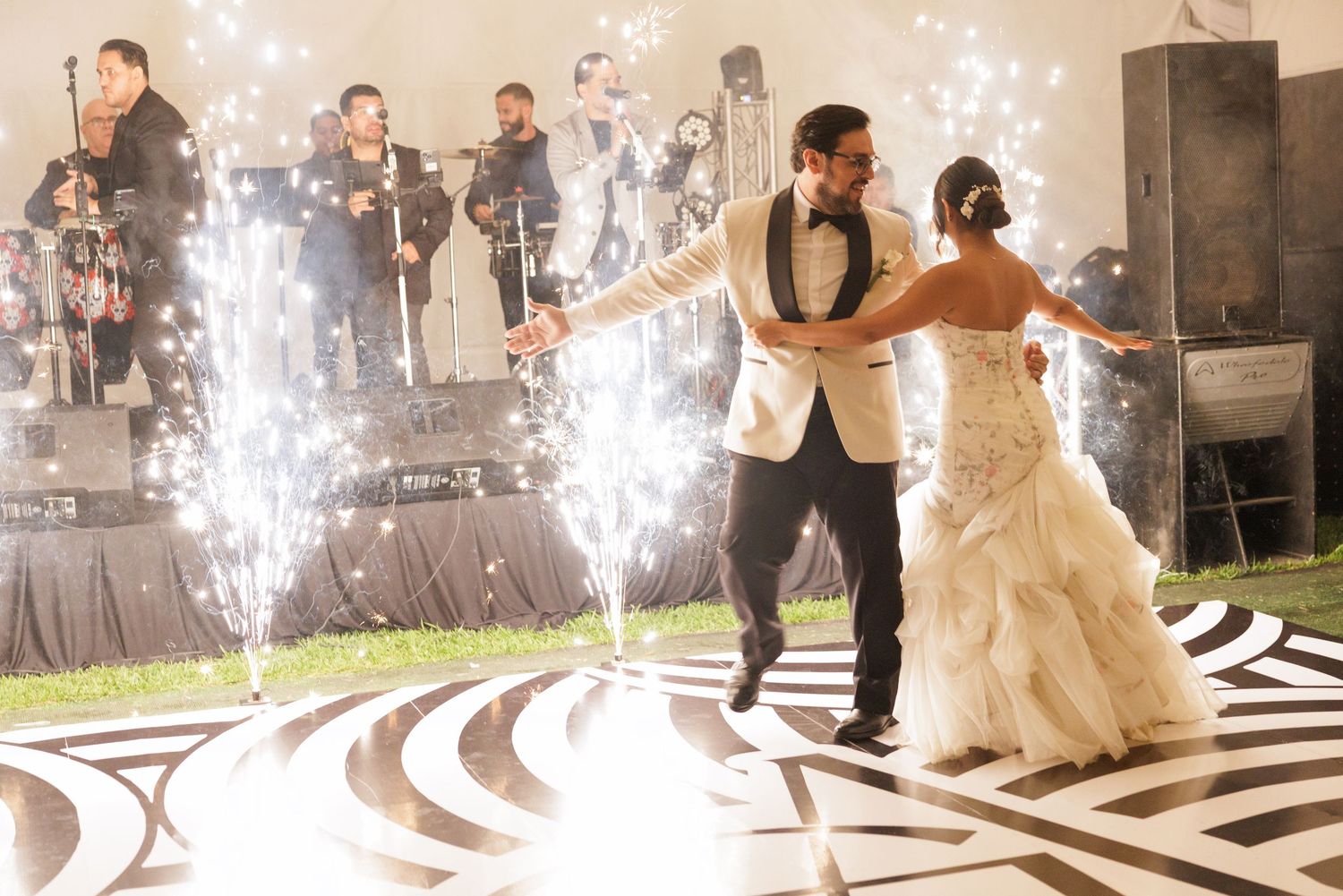 Wedding couple performs first dance with sparklers creating magical light effects on dance floor.