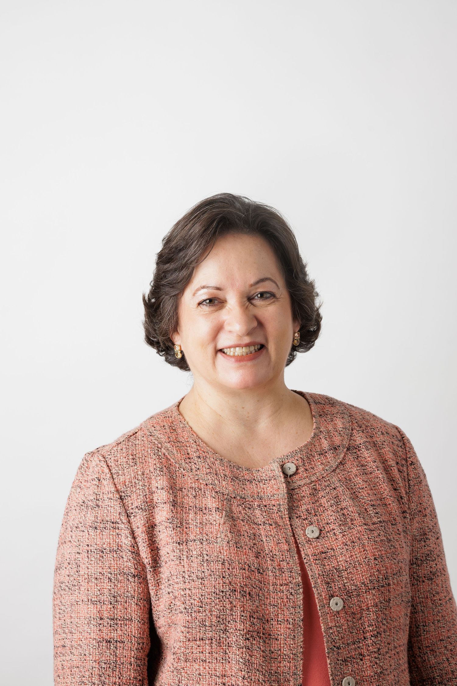 Professional headshot of someone wearing a coral tweed jacket against white background.