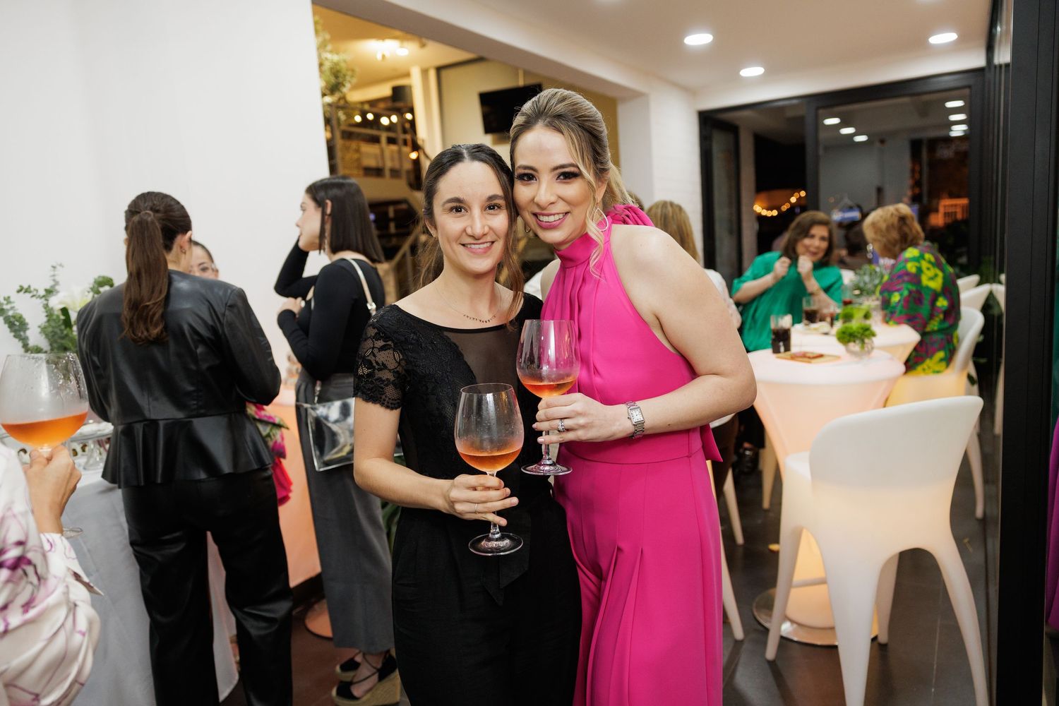 Two guests enjoy wine and conversation at an elegant boutique event.